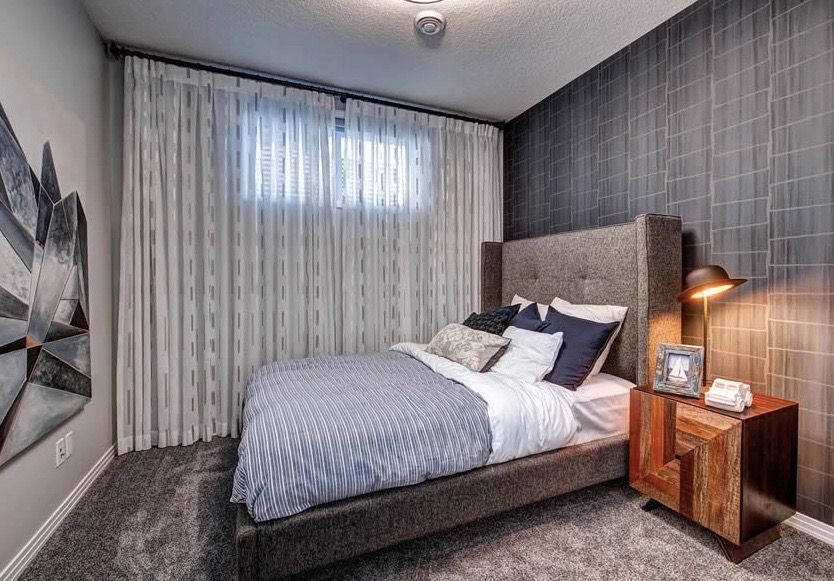 A bedroom with a bed , nightstand , lamp and window.