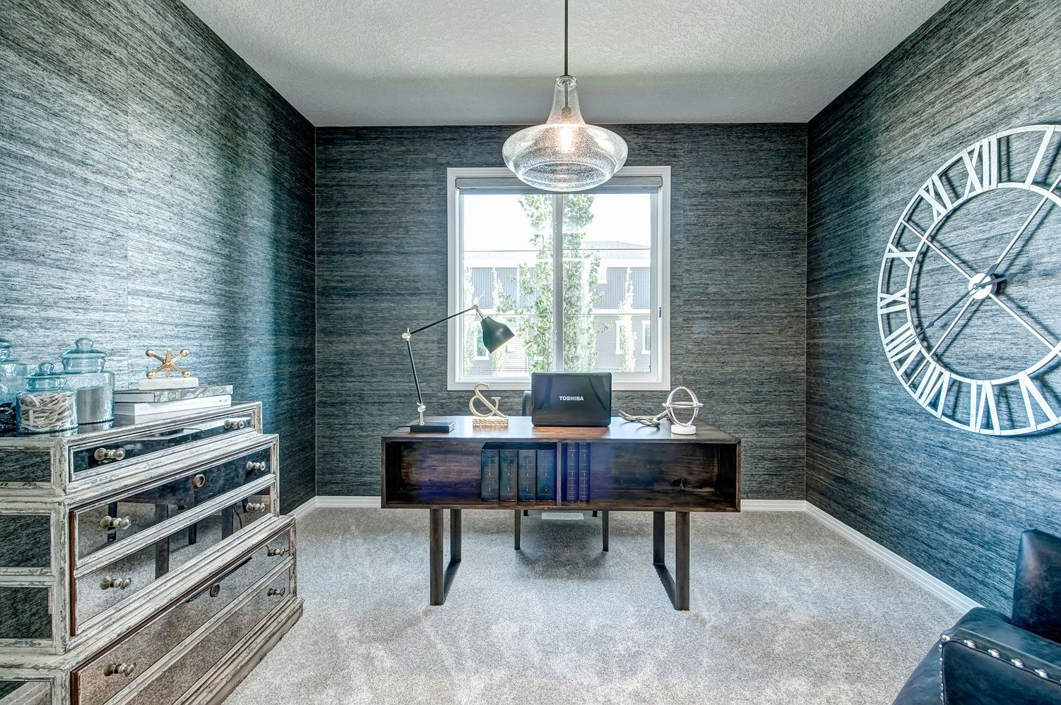 A home office with a desk and a large clock on the wall.