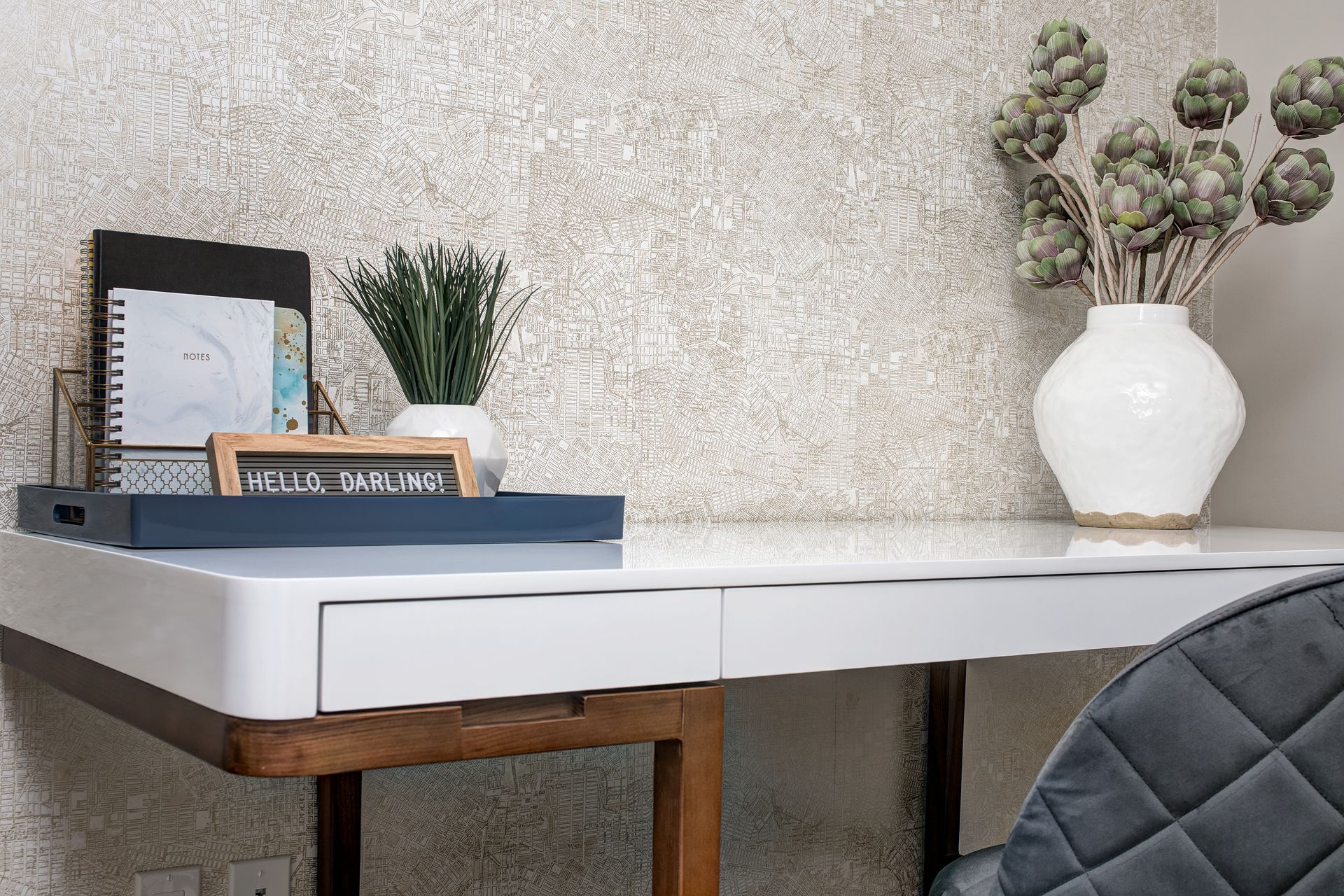 A white desk with a vase of flowers on top of it.