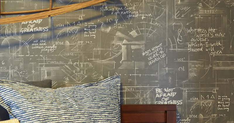 A bedroom with a chalkboard wall and a pillow on the bed