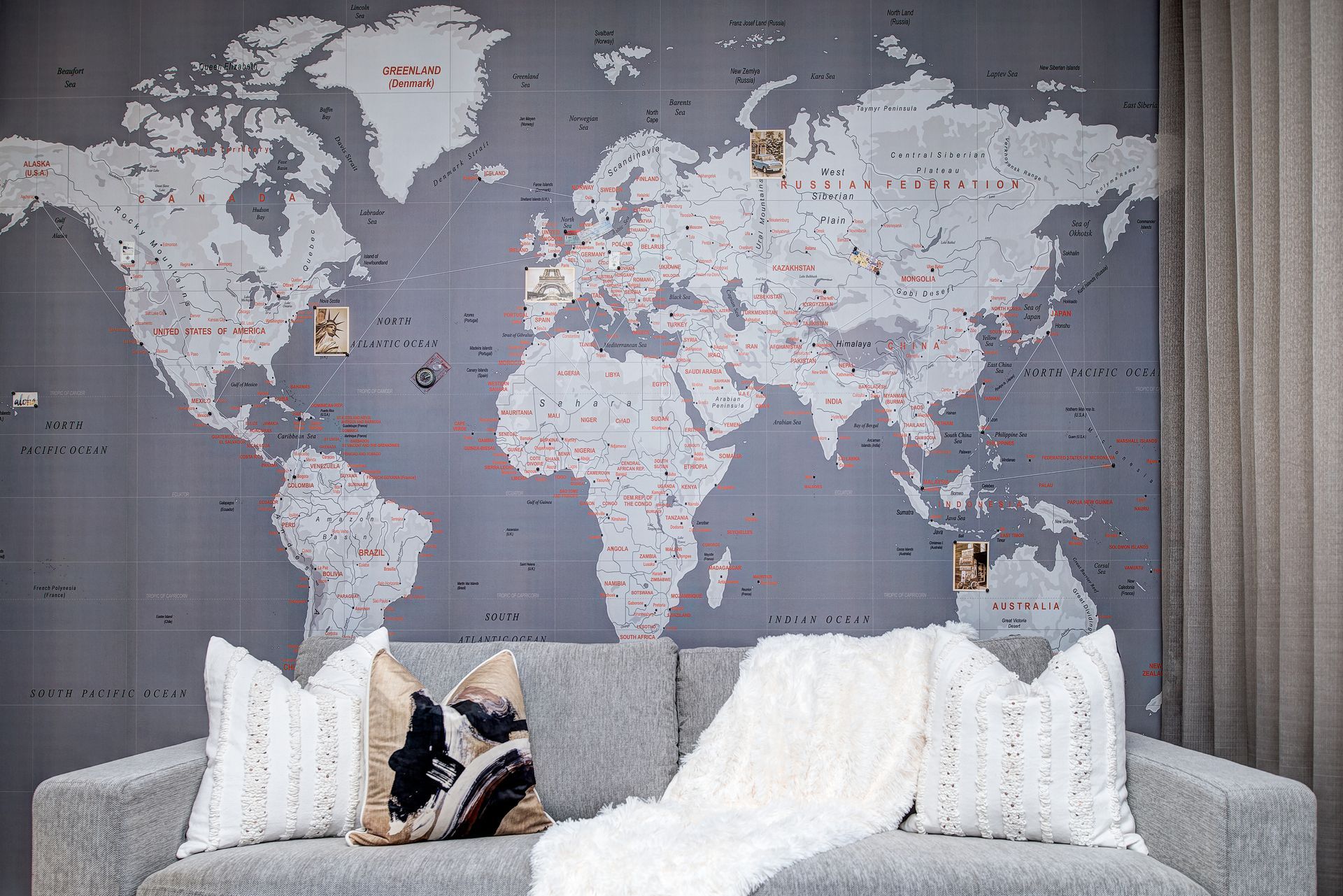A living room with a couch and a large map of the world on the wall.