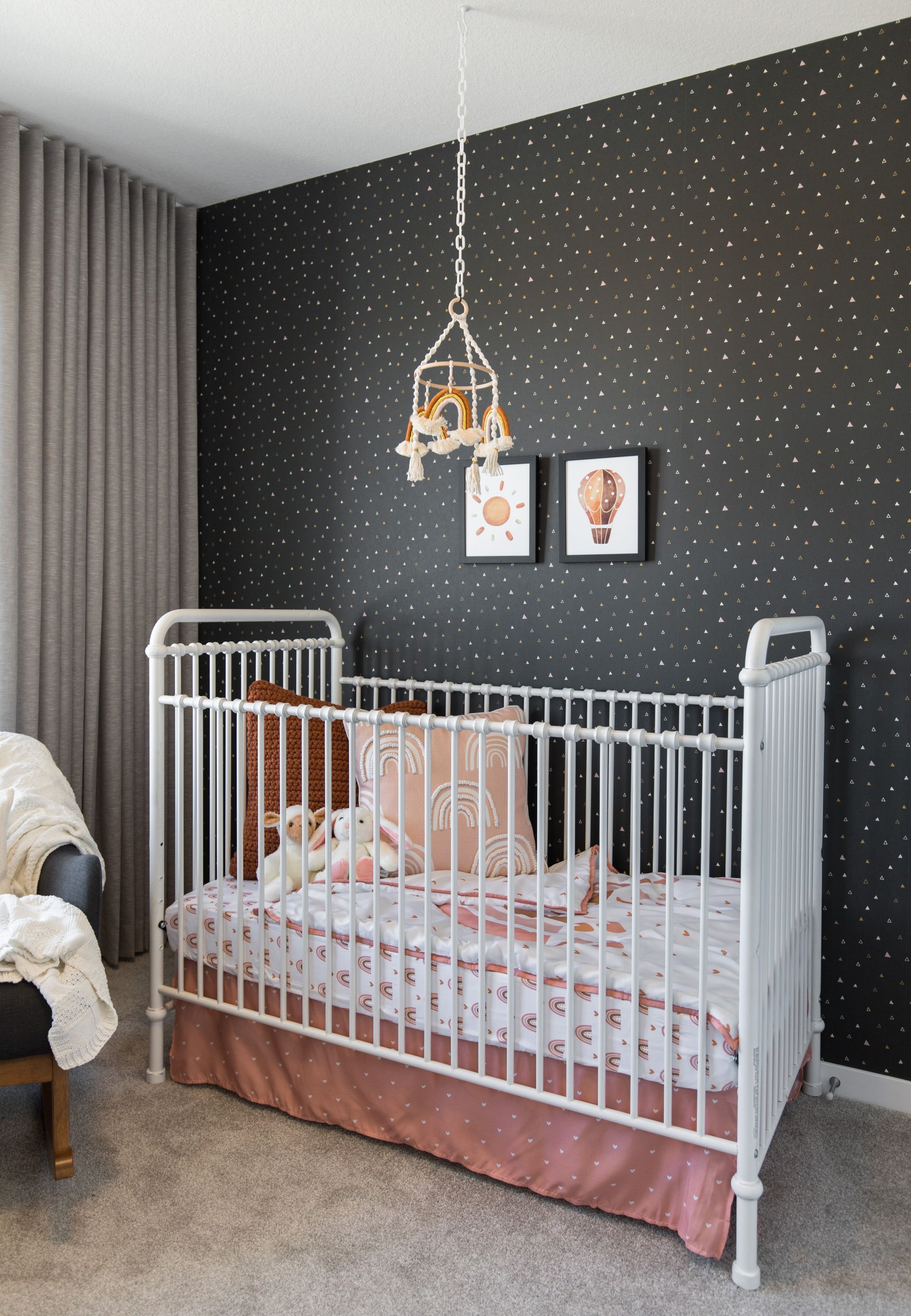 A white crib is in a nursery with a black wall.