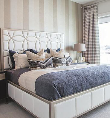 A bedroom with a king size bed and striped wallpaper.