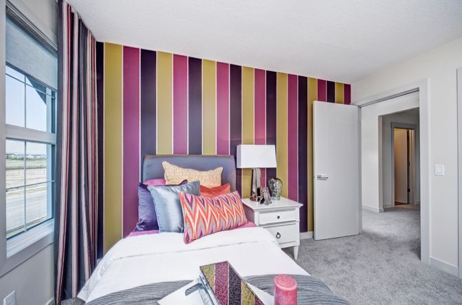 A bedroom with a striped wall and a bed.