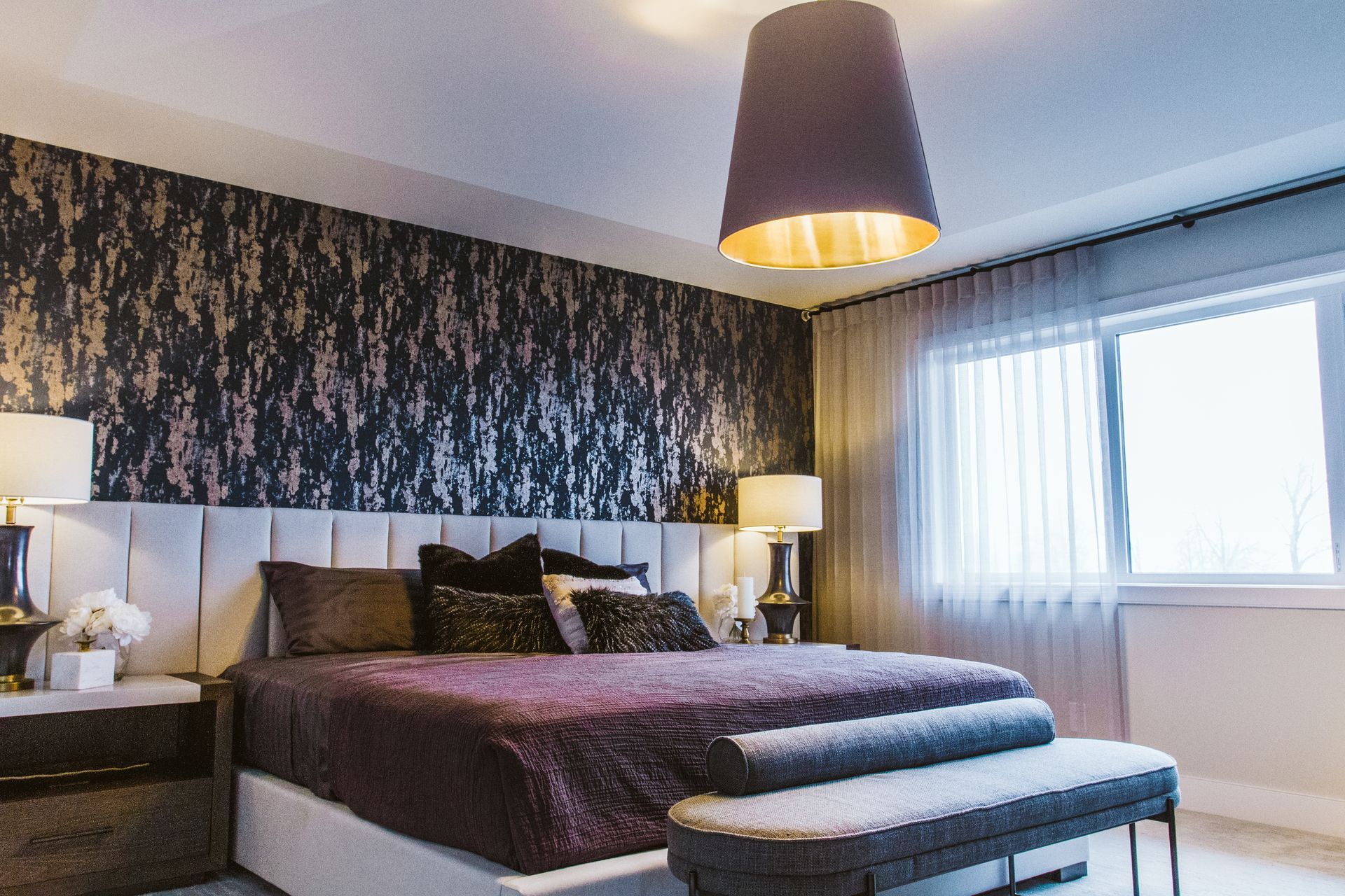 A bedroom with a large bed , nightstands , lamps and a window.