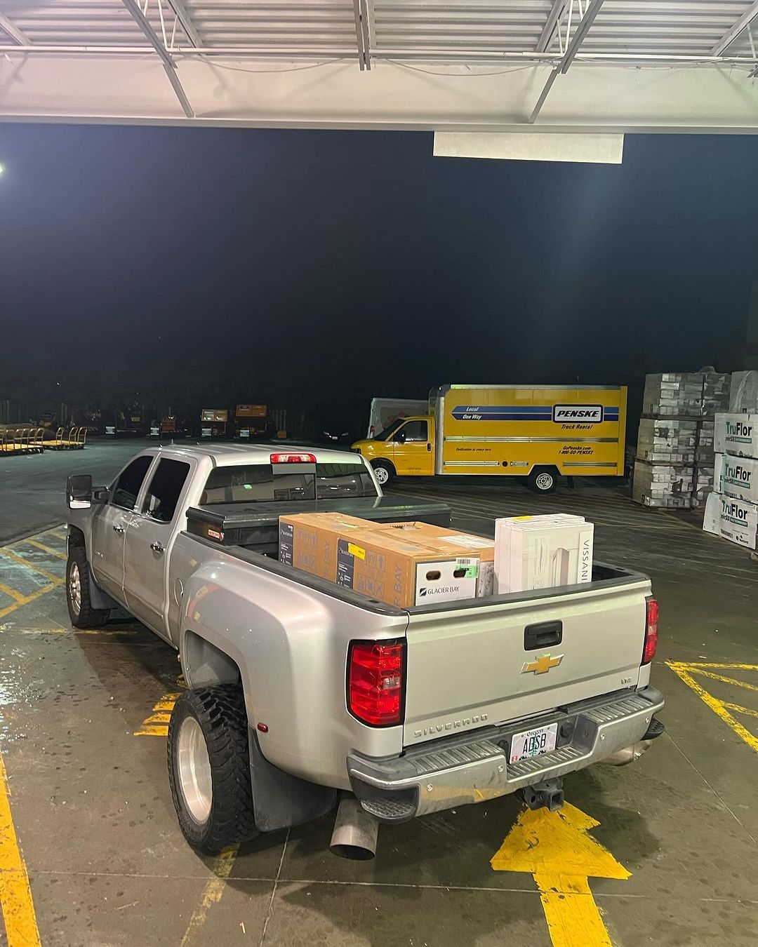 A silver truck is parked in a parking lot with boxes in the bed.