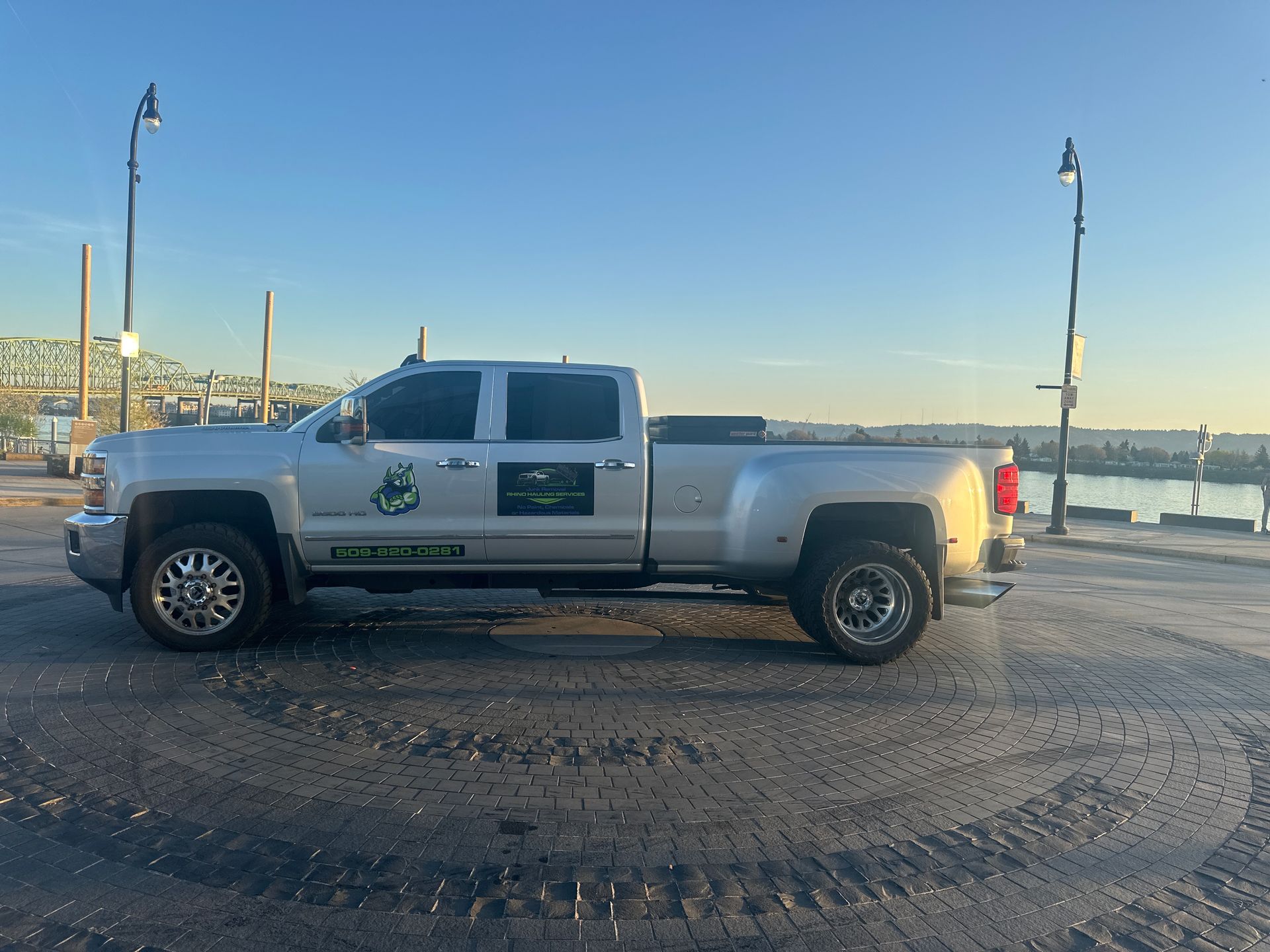 A silver truck is parked in a parking lot next to a body of water.