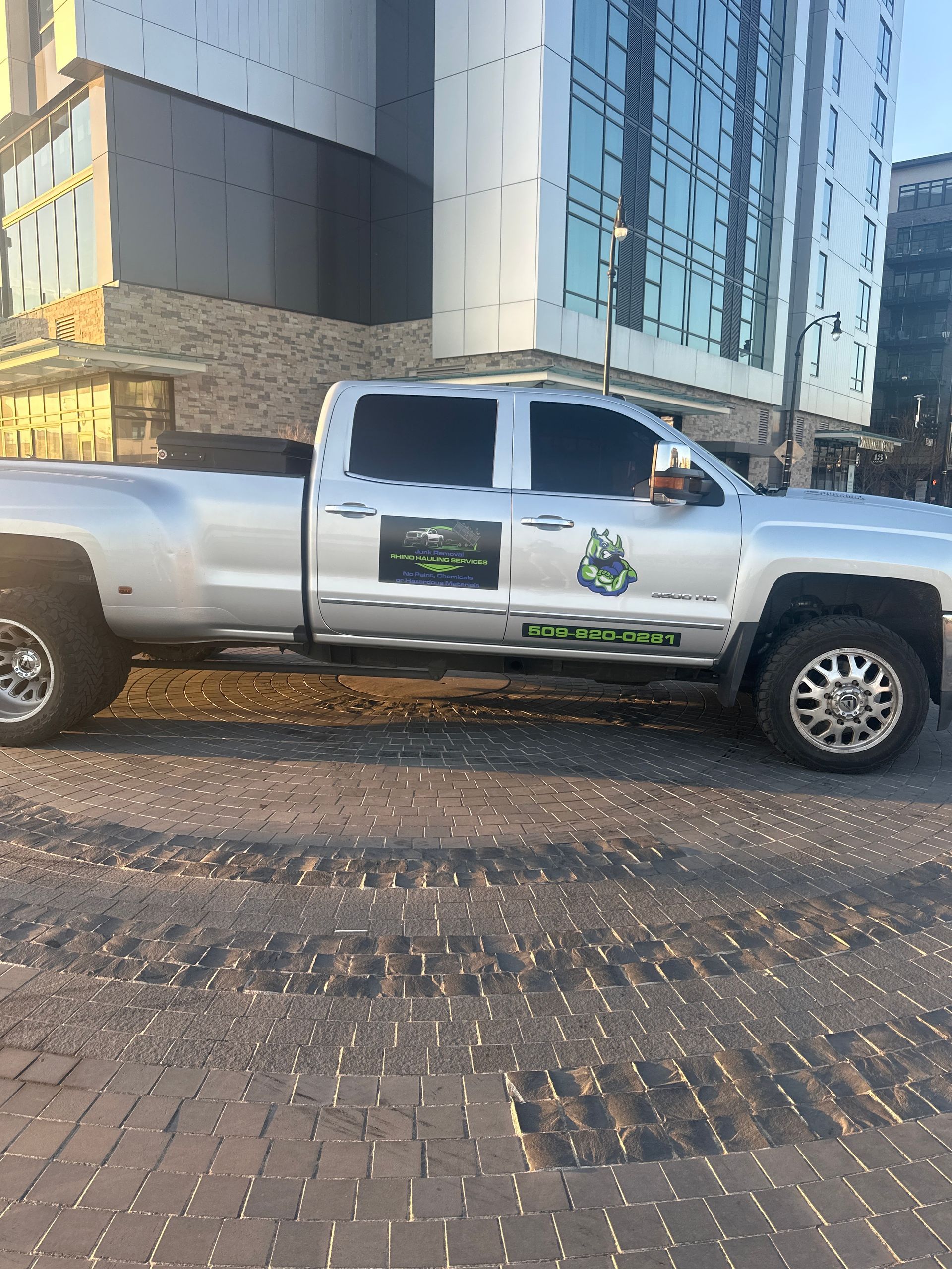 A white truck is parked on a brick sidewalk in front of a building.