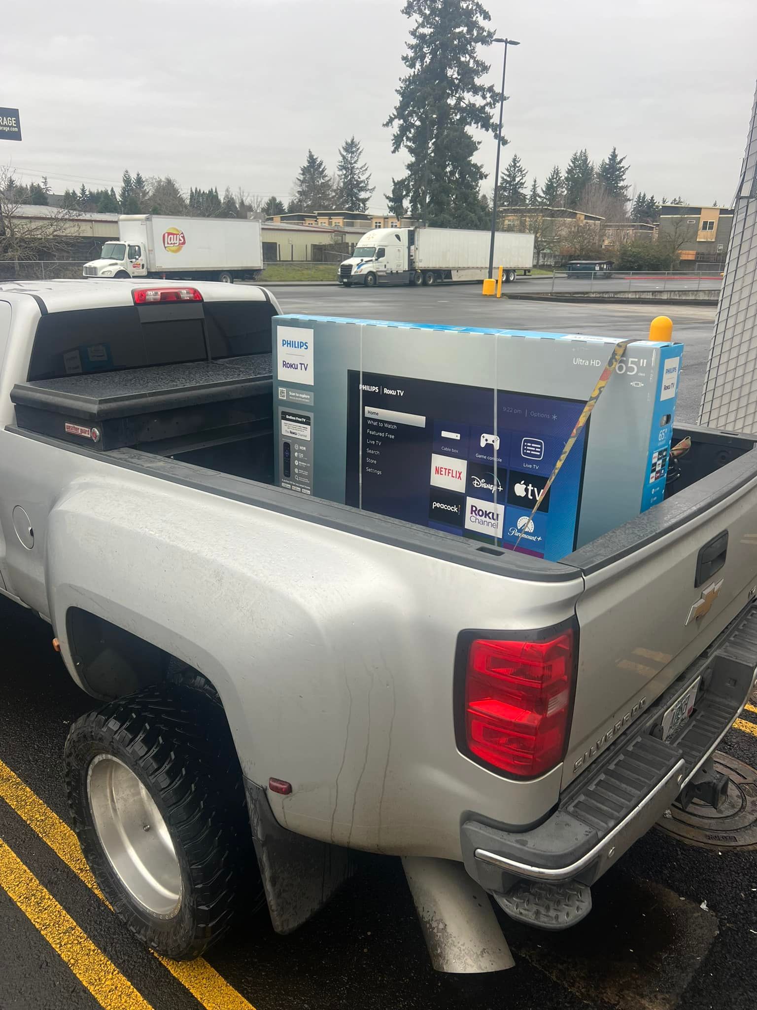 A silver truck with boxes in the back is parked in a parking lot