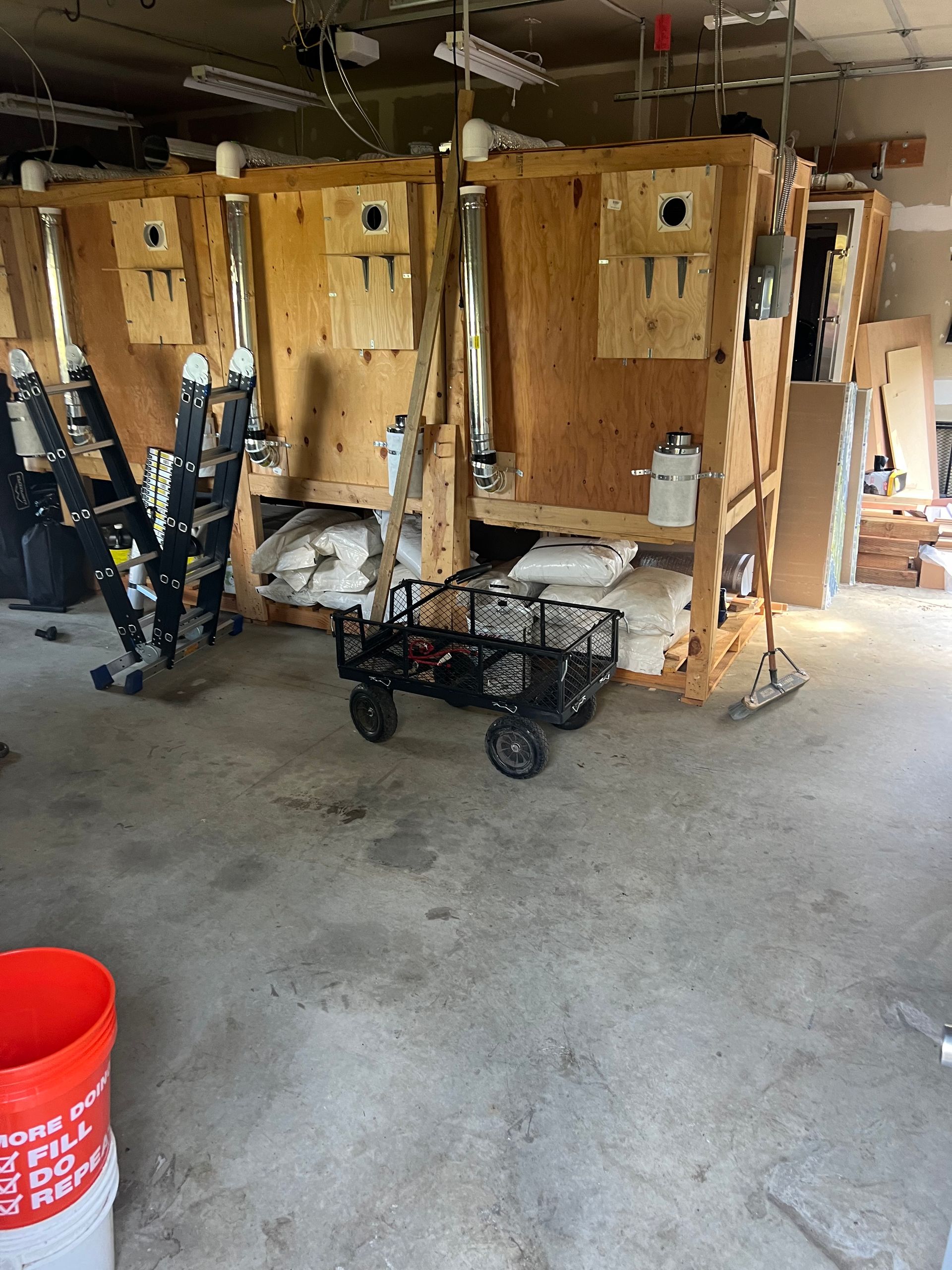 A large room with a cart and a bucket of paint on the floor.