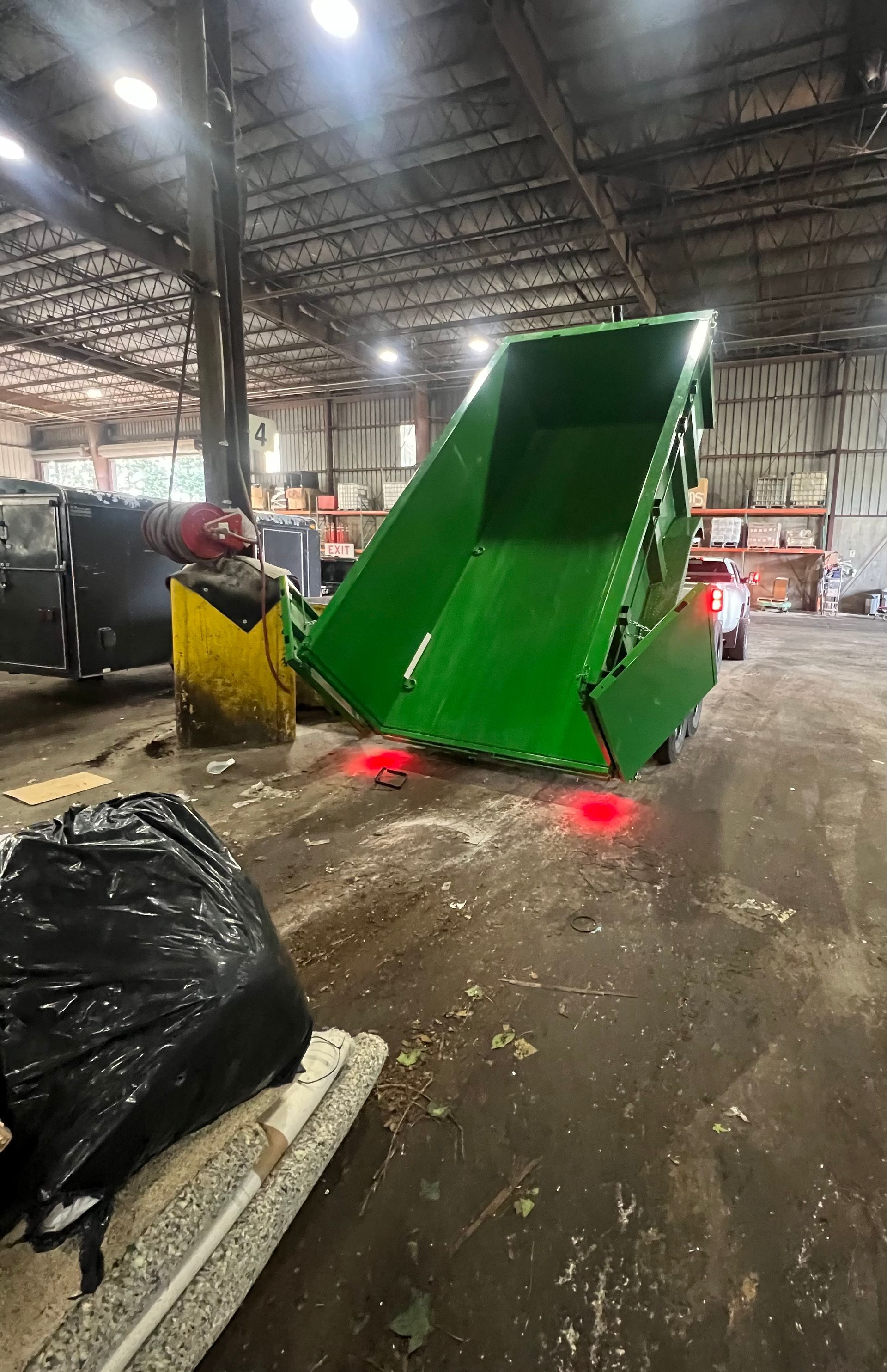A green dumpster is sitting in a warehouse.