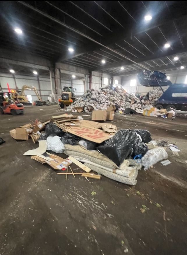 A large warehouse filled with lots of trash and cardboard boxes.