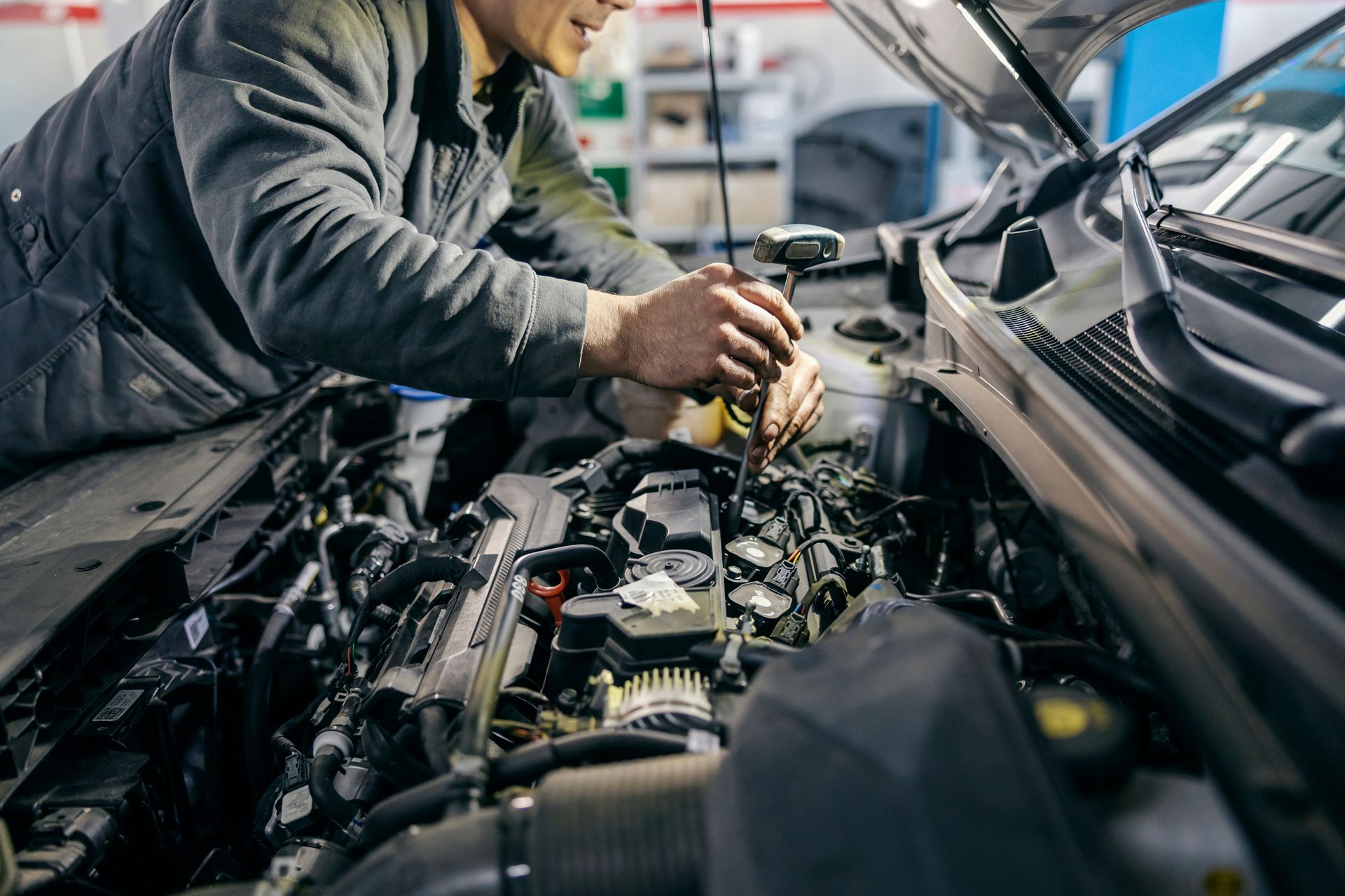 A man is working on the engine of a car in a garage.