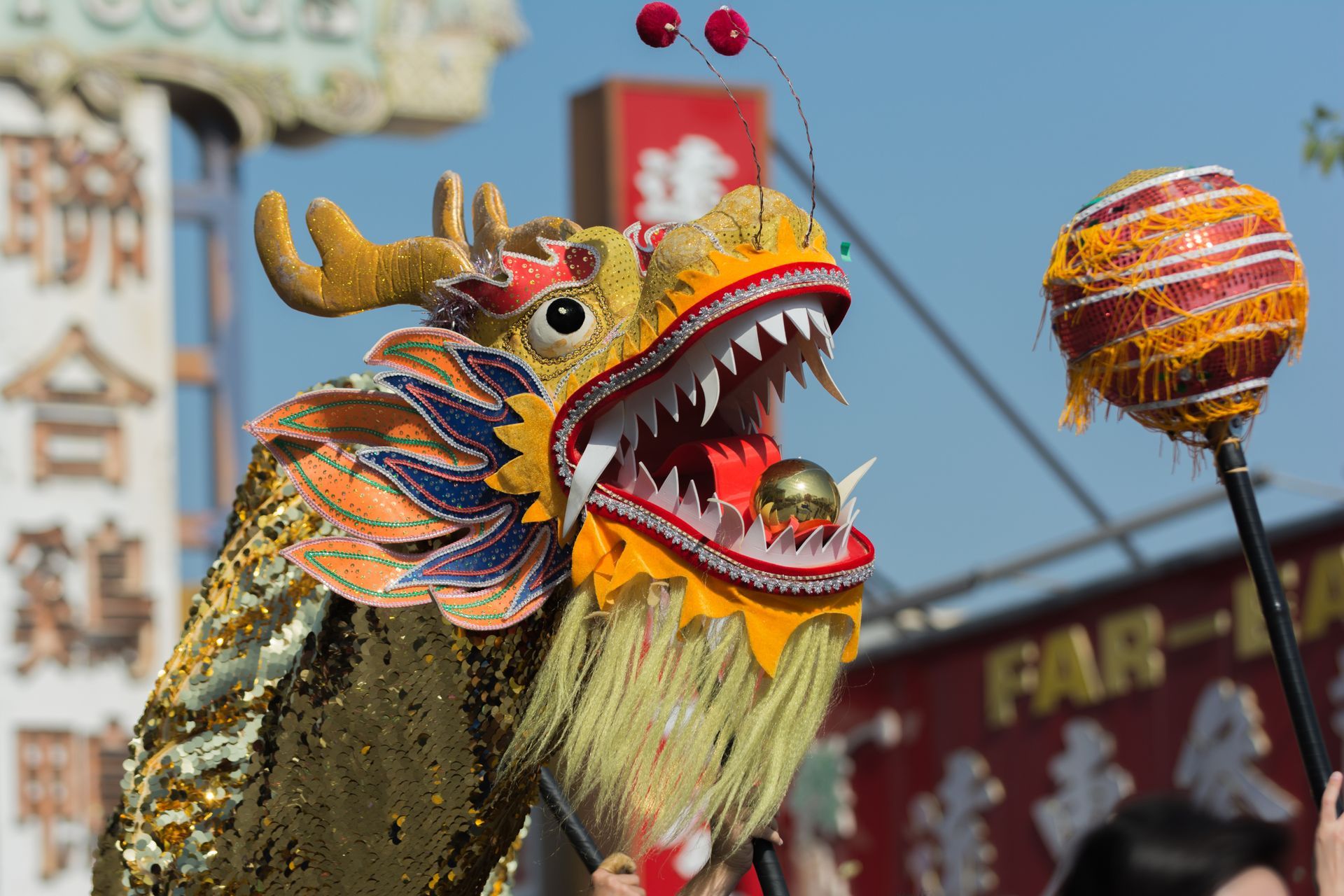 Gold and orange Chinese dragon puppet with open mouth, held in celebration.