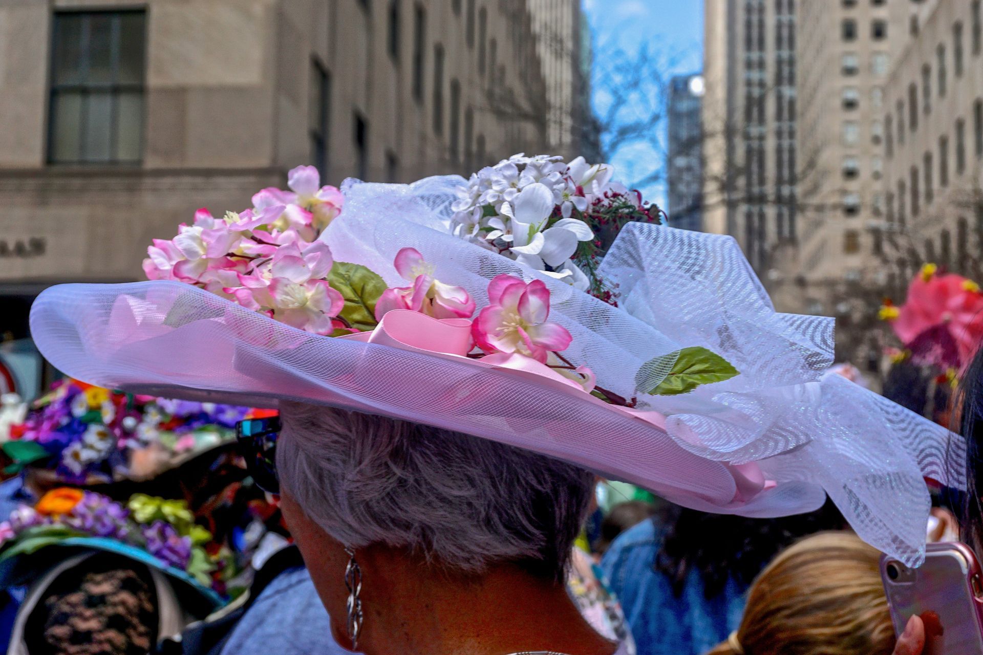 A woman is wearing a pink hat with flowers on it.