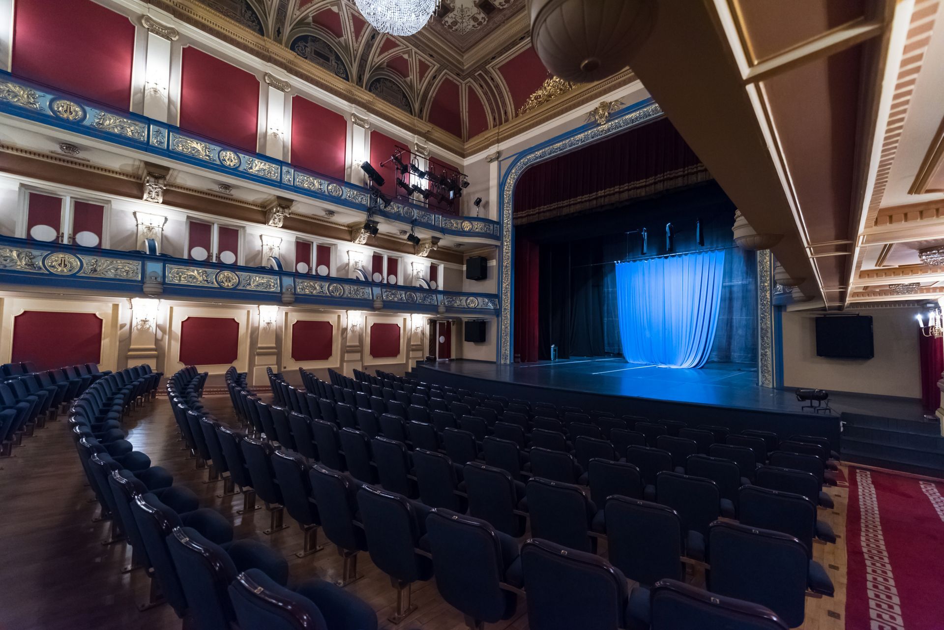 A large empty auditorium with rows of seats and a stage.