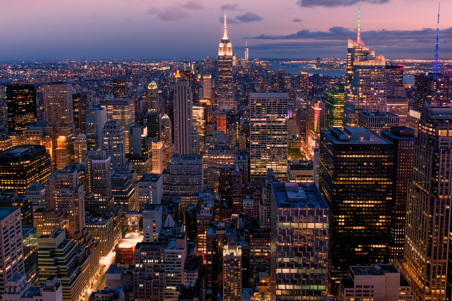 An aerial view of a city at night with the empire state building in the background