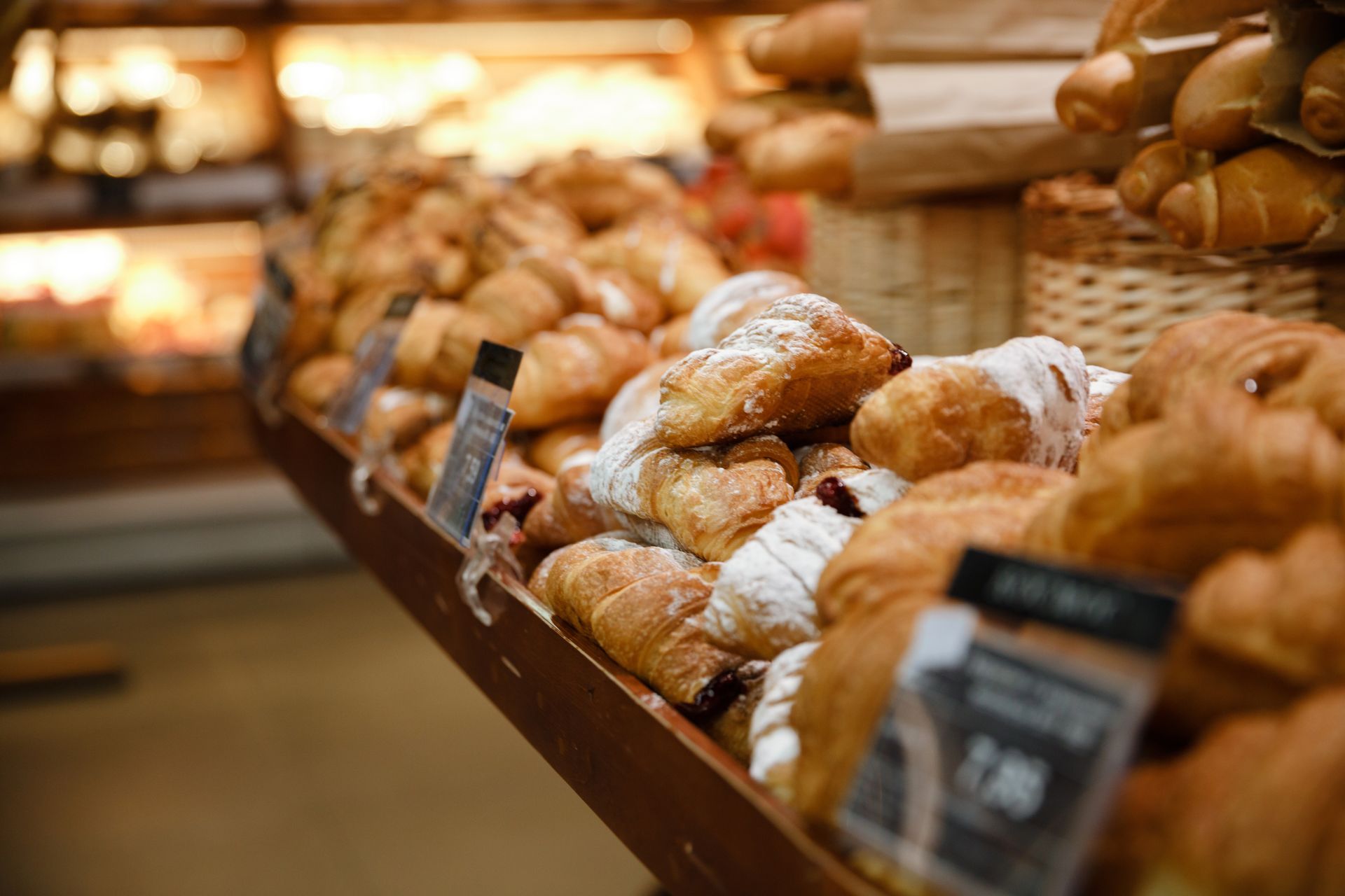 There are many different types of croissants on display in a bakery.