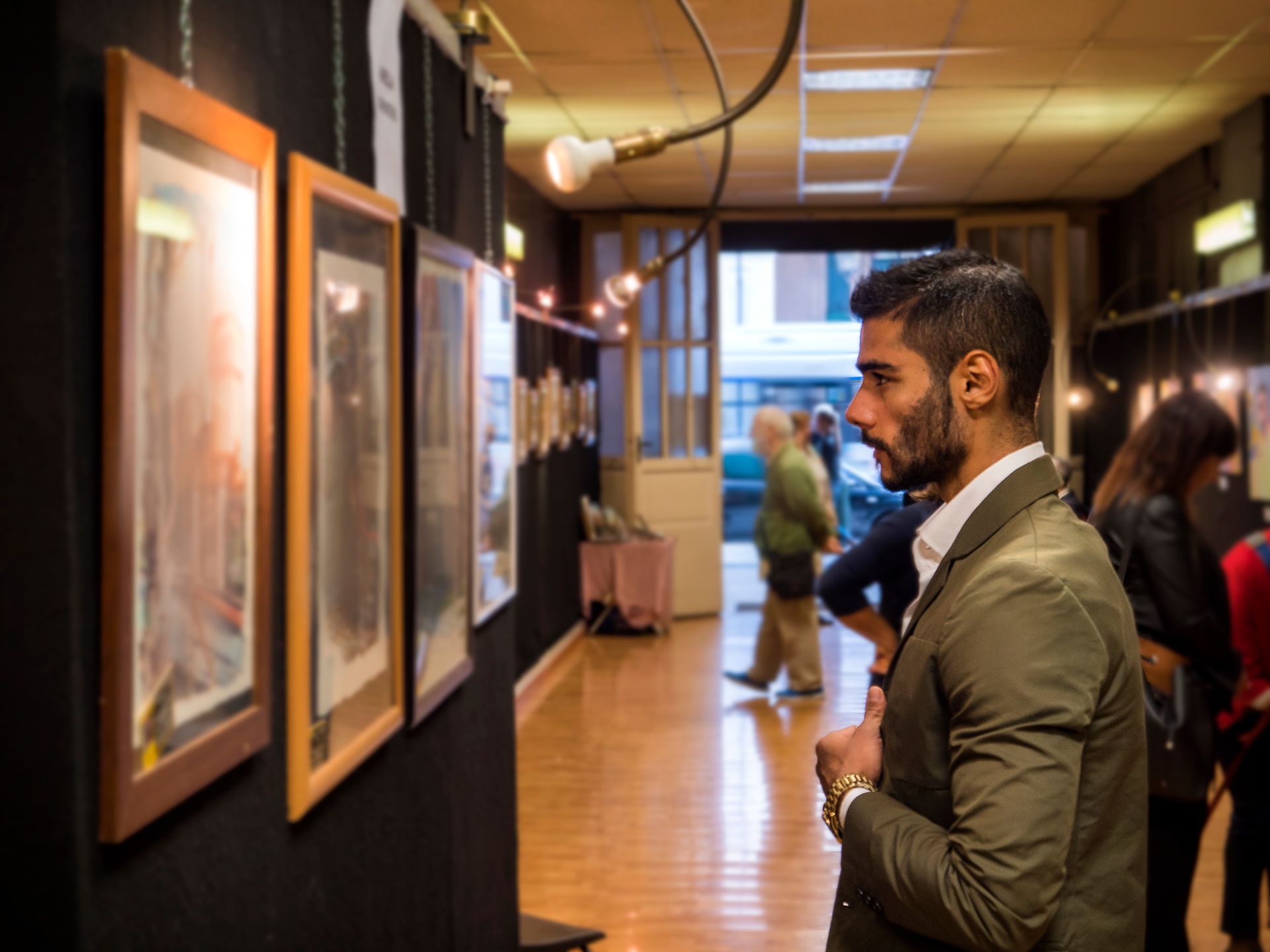 A man in a suit is looking at a painting  in an art gallery.