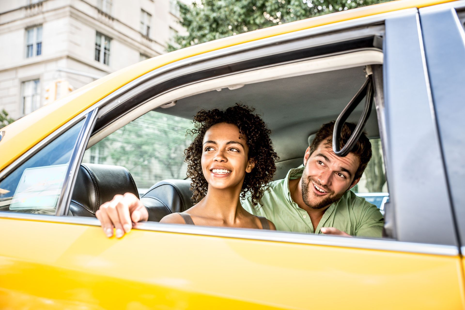 A man and a woman are sitting in a taxi looking out the window.