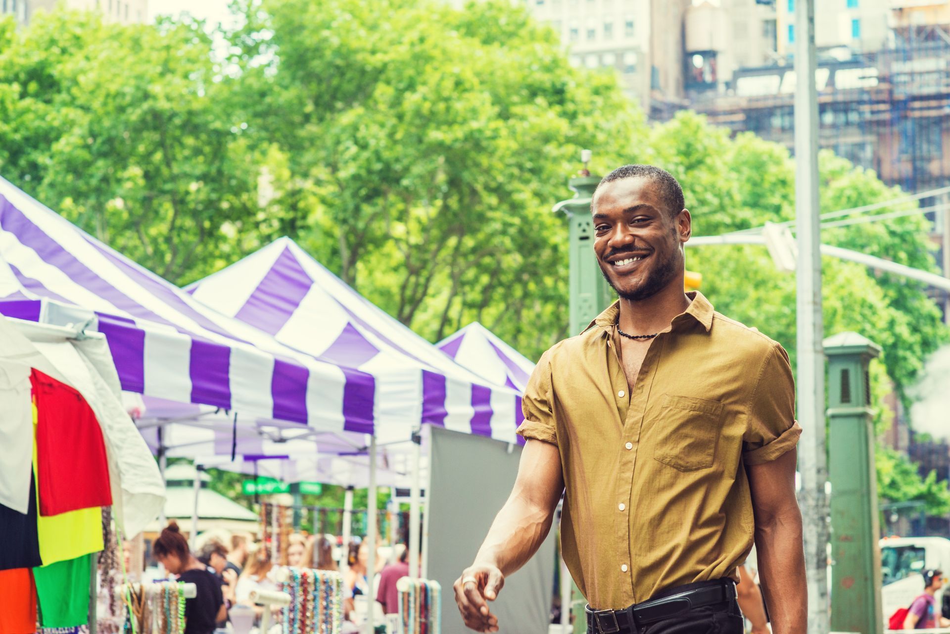 A man is walking down a street in front of a market.