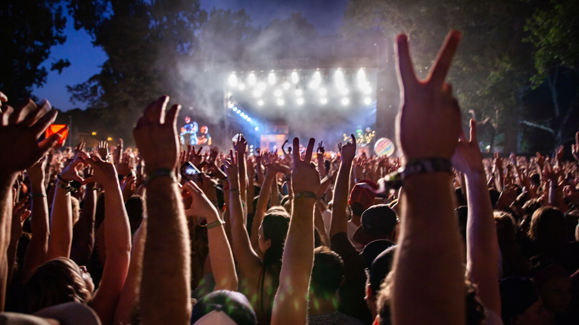 A crowd of people at a concert with their hands in the air.