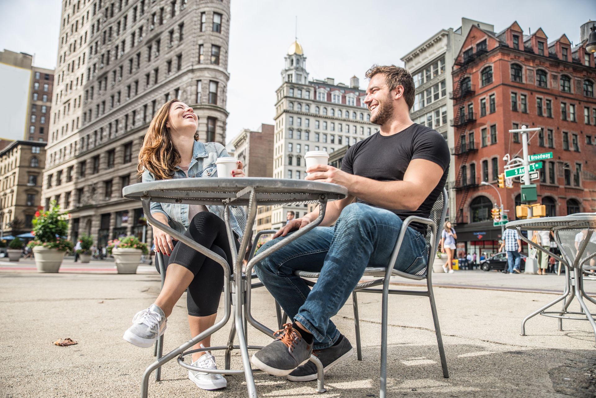 A man and a woman are sitting at a table in a city.