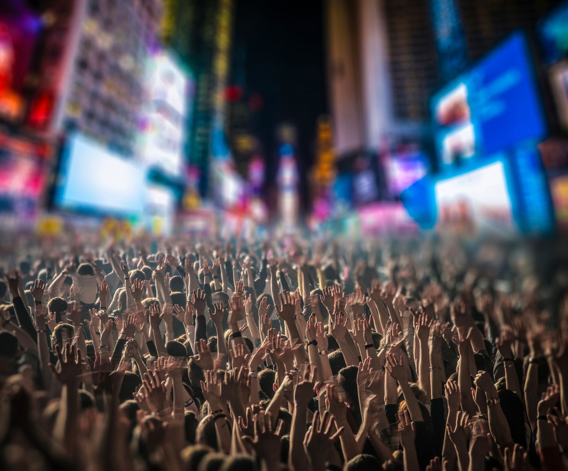 A crowd of people with their hands in the air in Times Square.