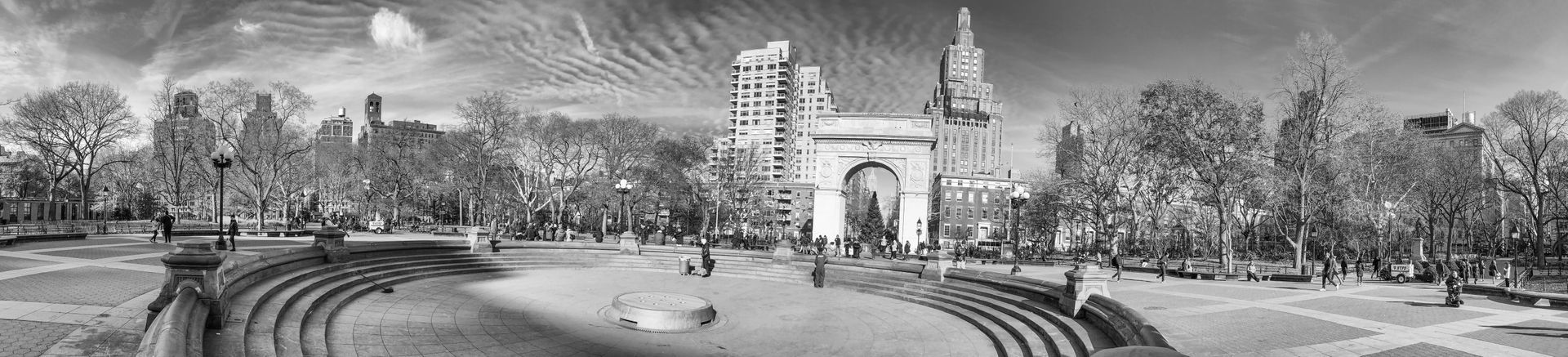 A black and white photo of a park with a building in the background.