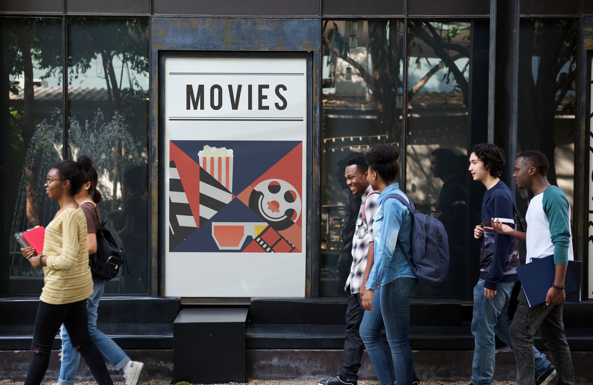 A group of people are walking in front of a movie poster.