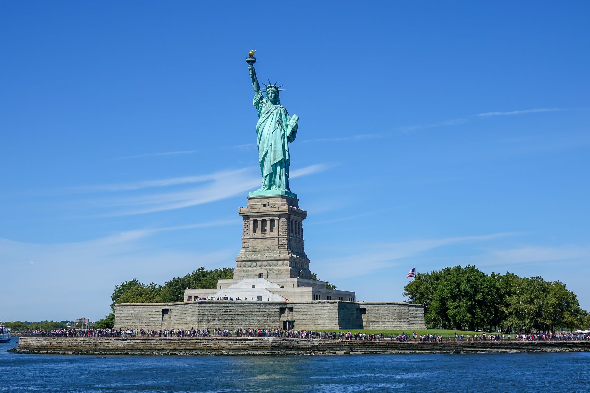 The statue of liberty is on a small island in the middle of the ocean.