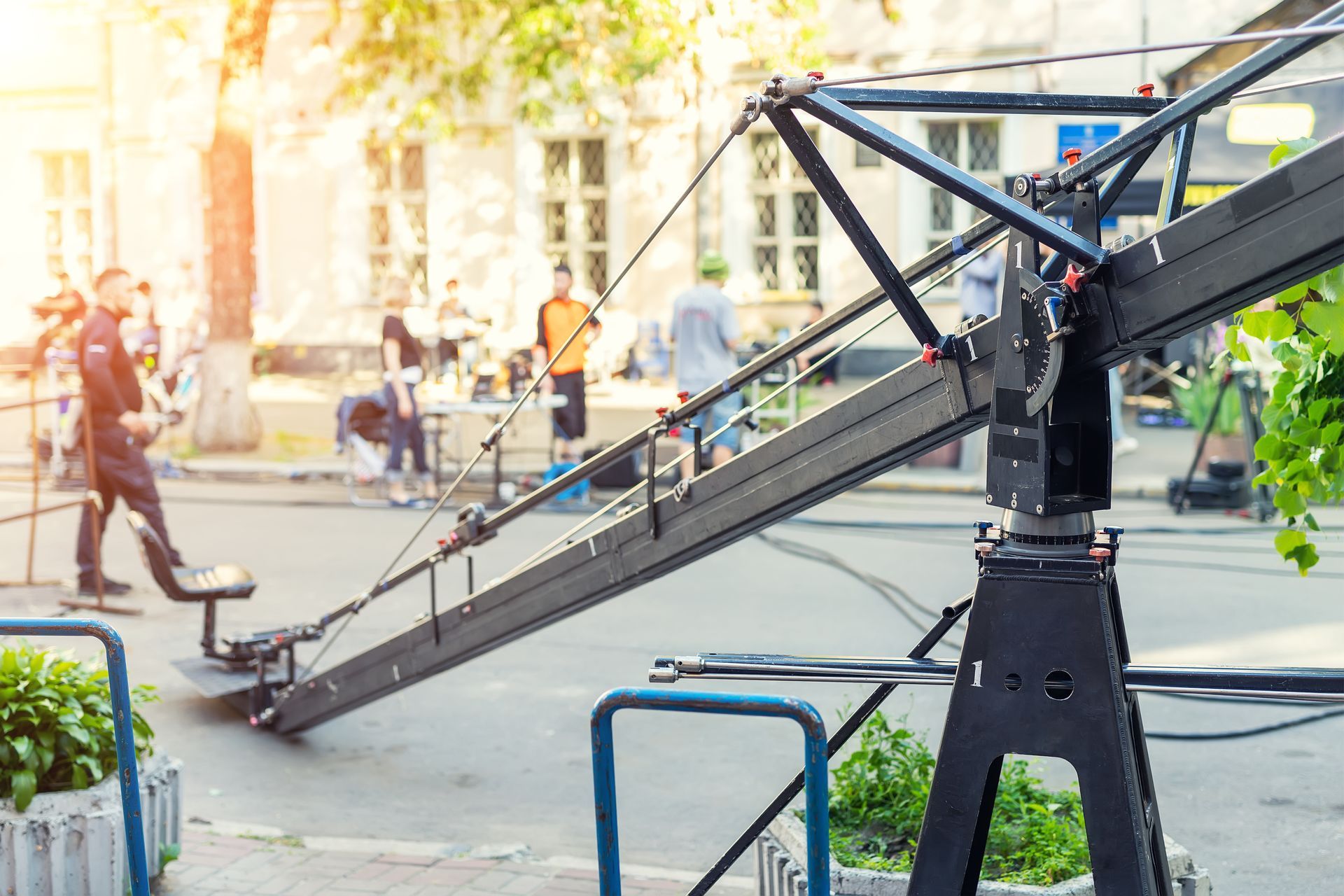 A large filming crane is sitting on the side of a street.