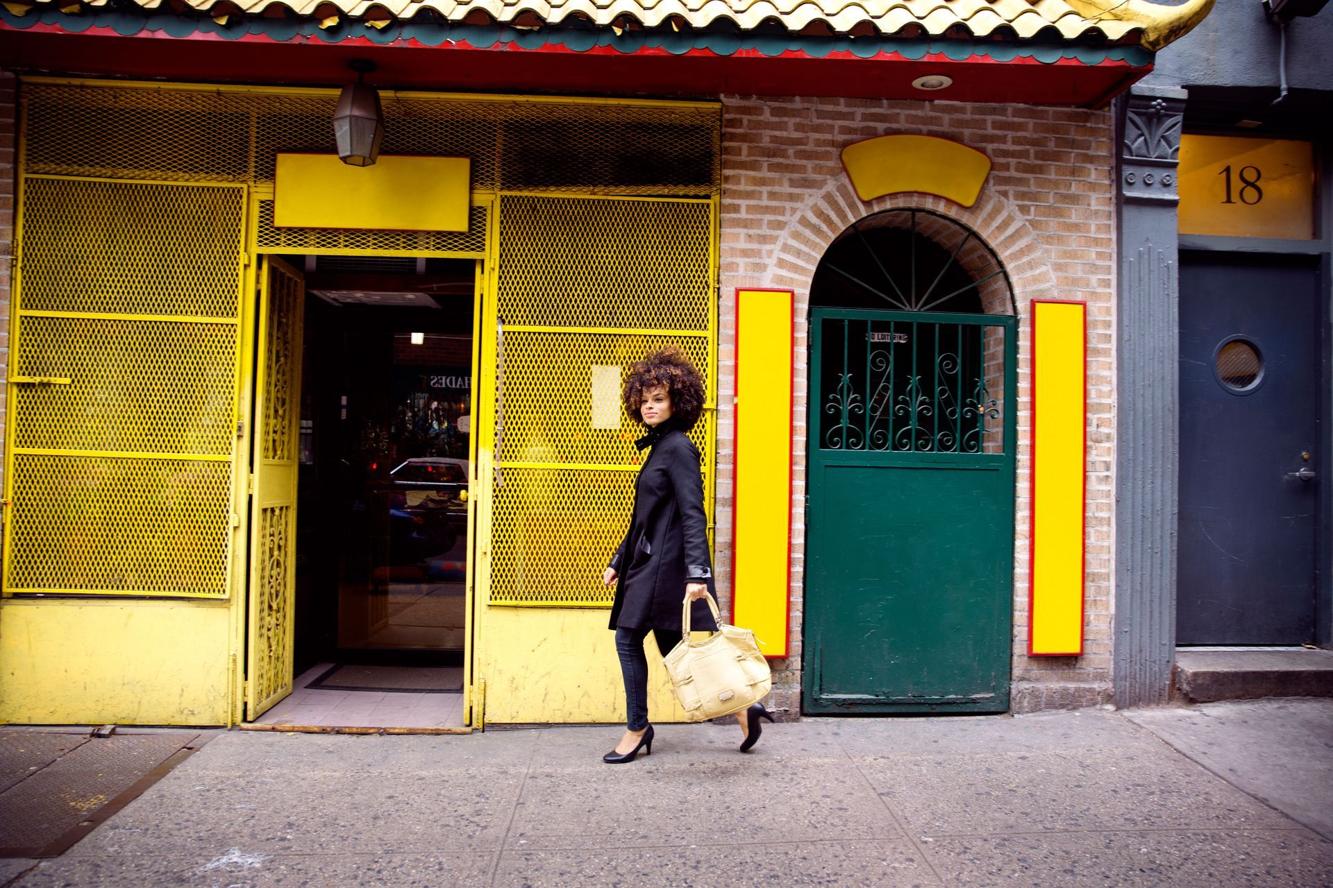 A woman walking in front of a building with the number 18 on it