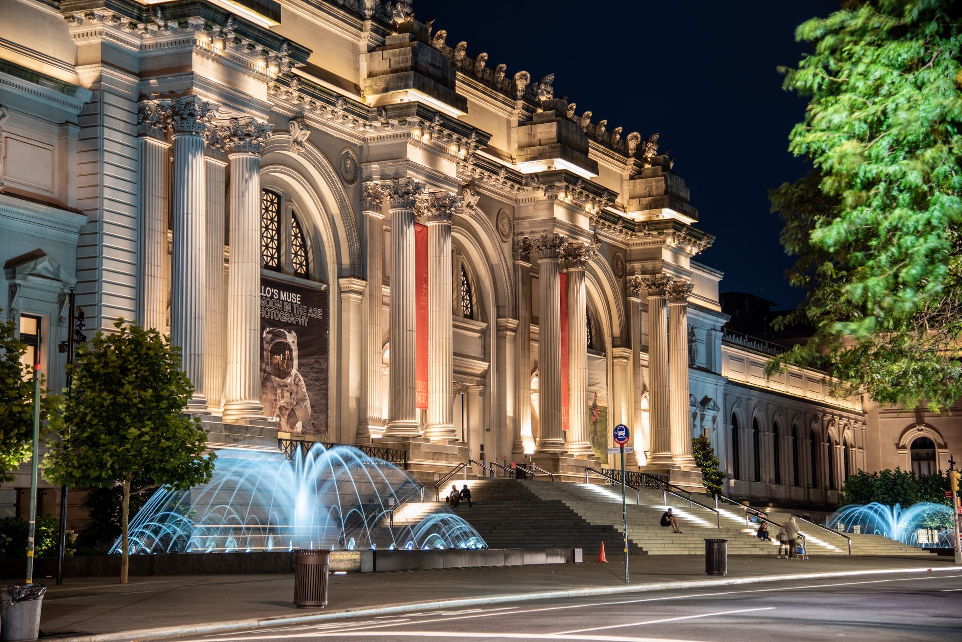 A large building with a fountain in front of it at night