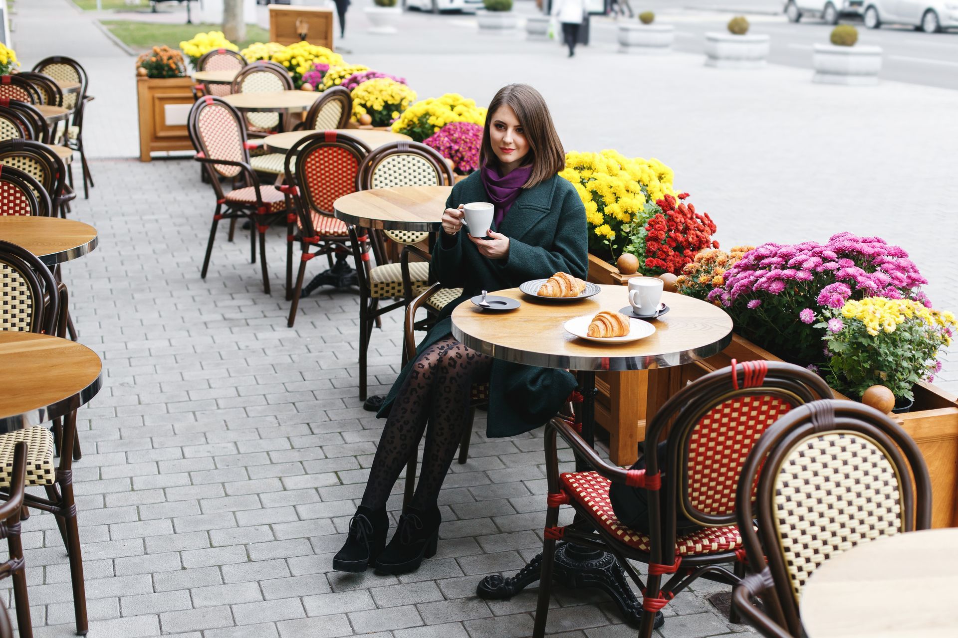 A woman is sitting at a table in a restaurant holding a cup of coffee.