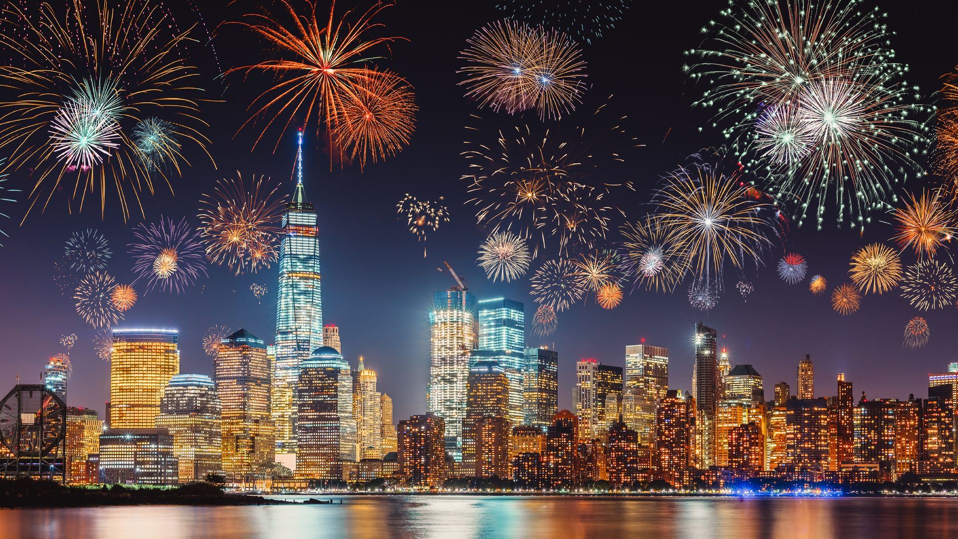 Fireworks are exploding over a city skyline at night.