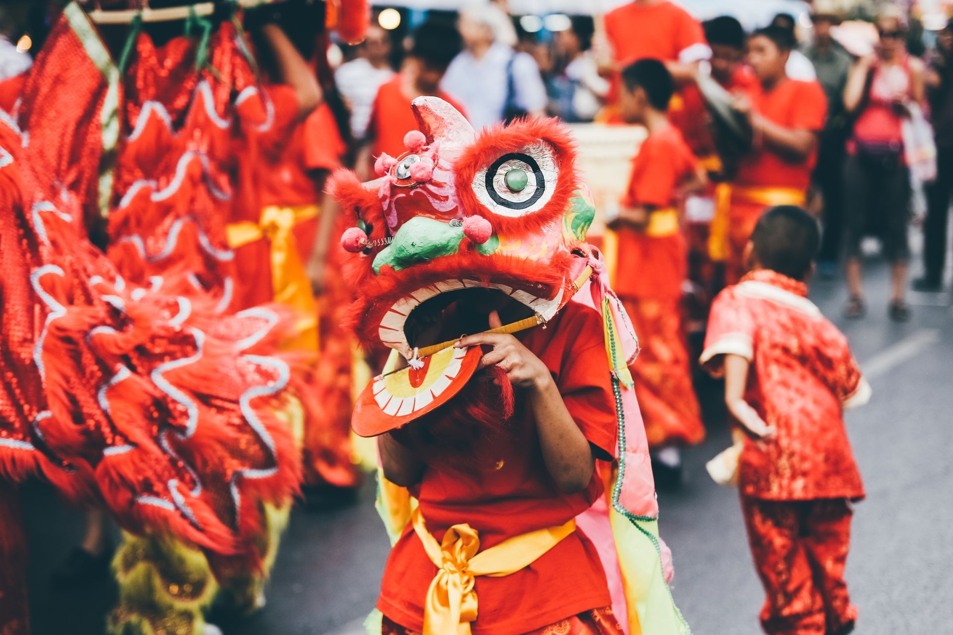 A group of people dressed in red and yellow costumes are dancing in a parade.