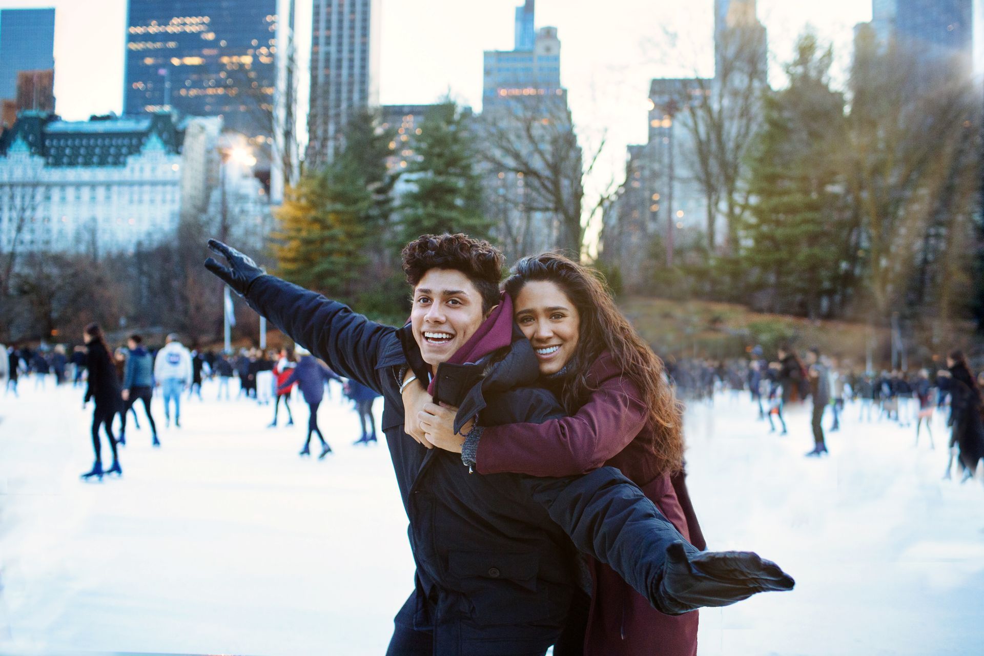 A man is giving a woman a piggyback ride on an ice rink.