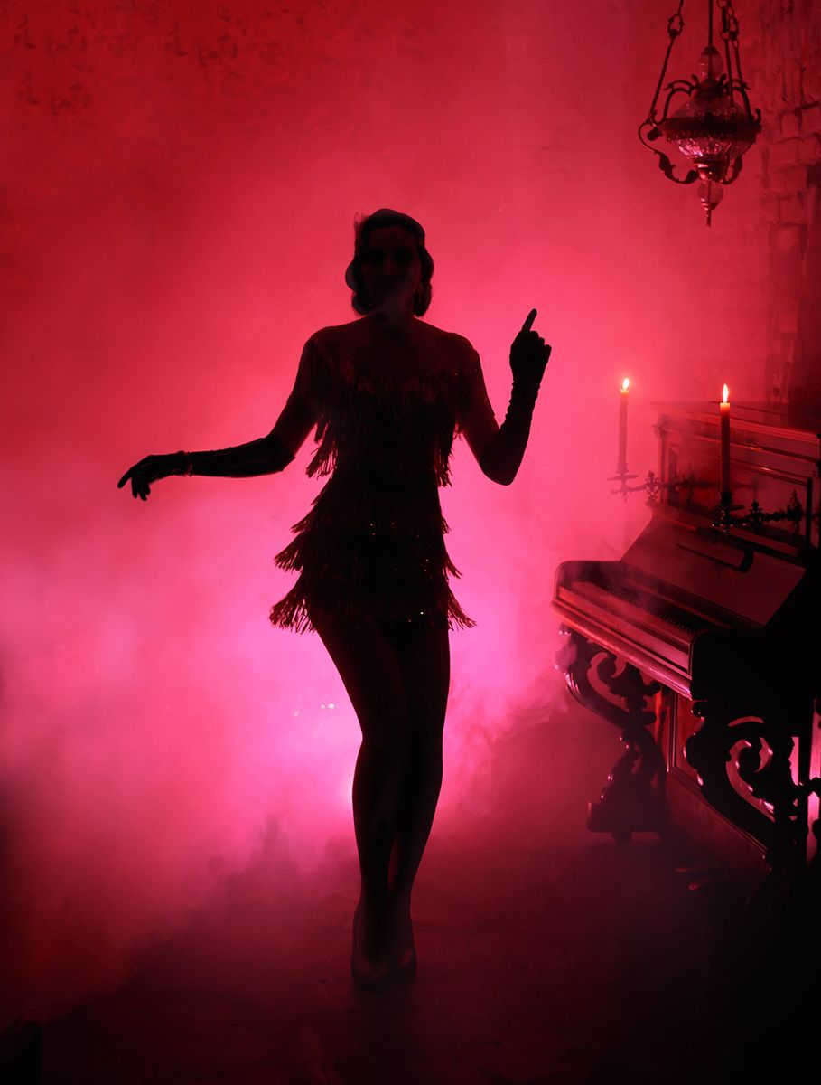a silhouette of a woman dancing in front of a piano