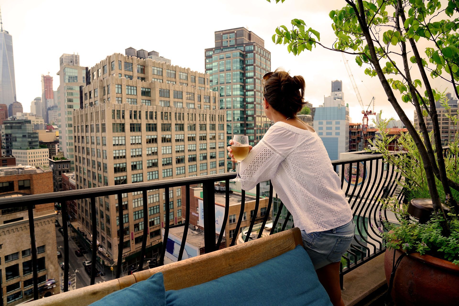 A woman is standing on a balcony looking out over a city