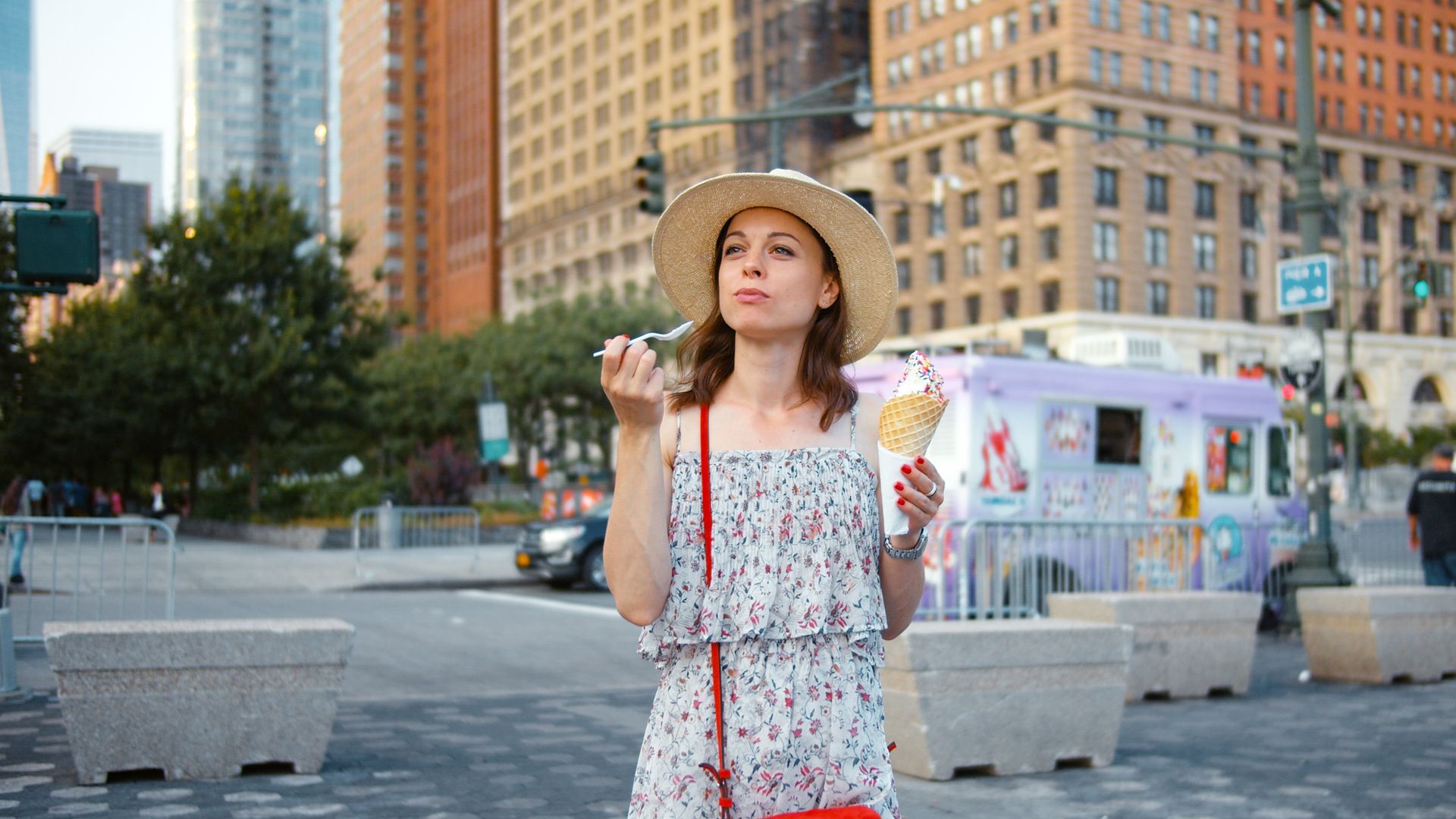 A woman is eating an ice cream cone on a city street.