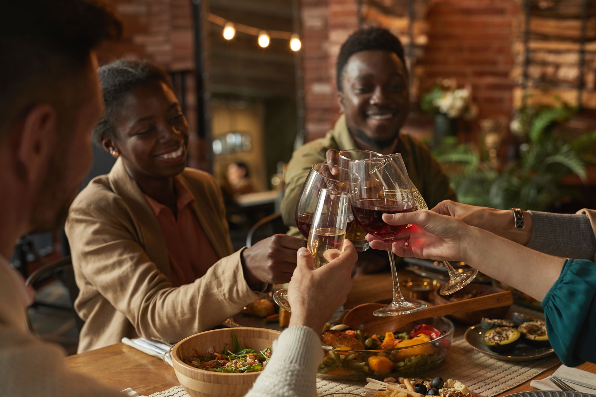 A group of people are sitting at a table toasting with wine glasses.