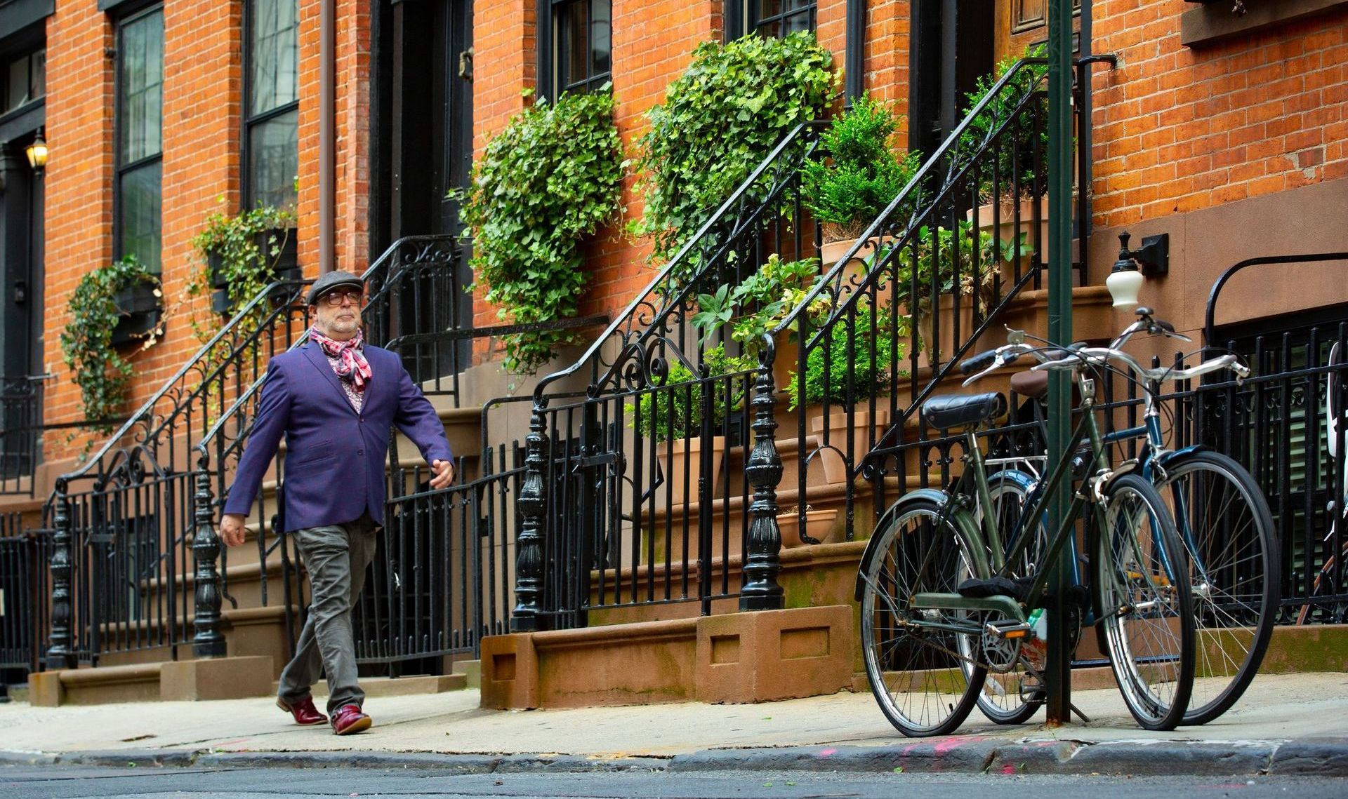 A man is walking down a sidewalk in front of a brick building.