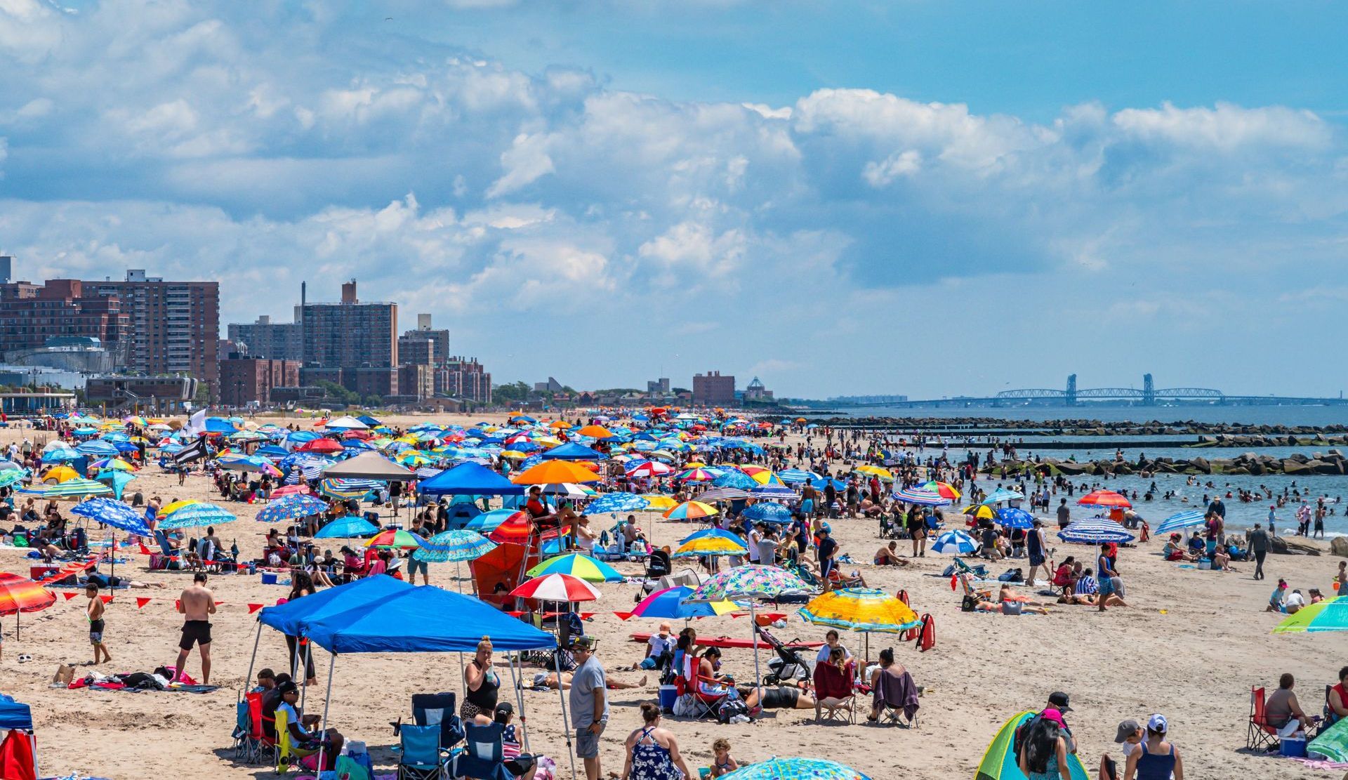 A crowded beach with umbrellas and tents on a sunny day.