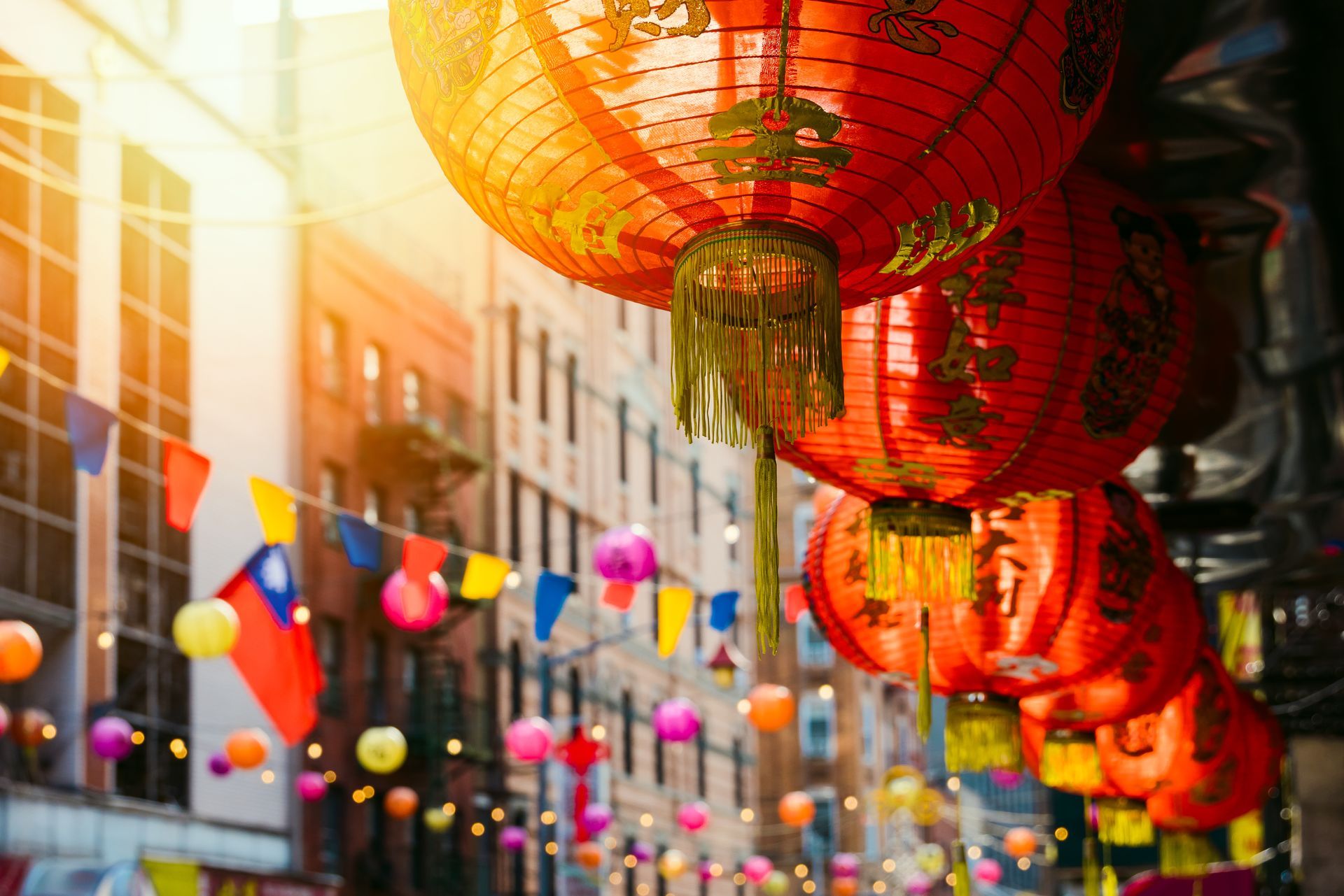 A bunch of lanterns are hanging from the ceiling in a city street.