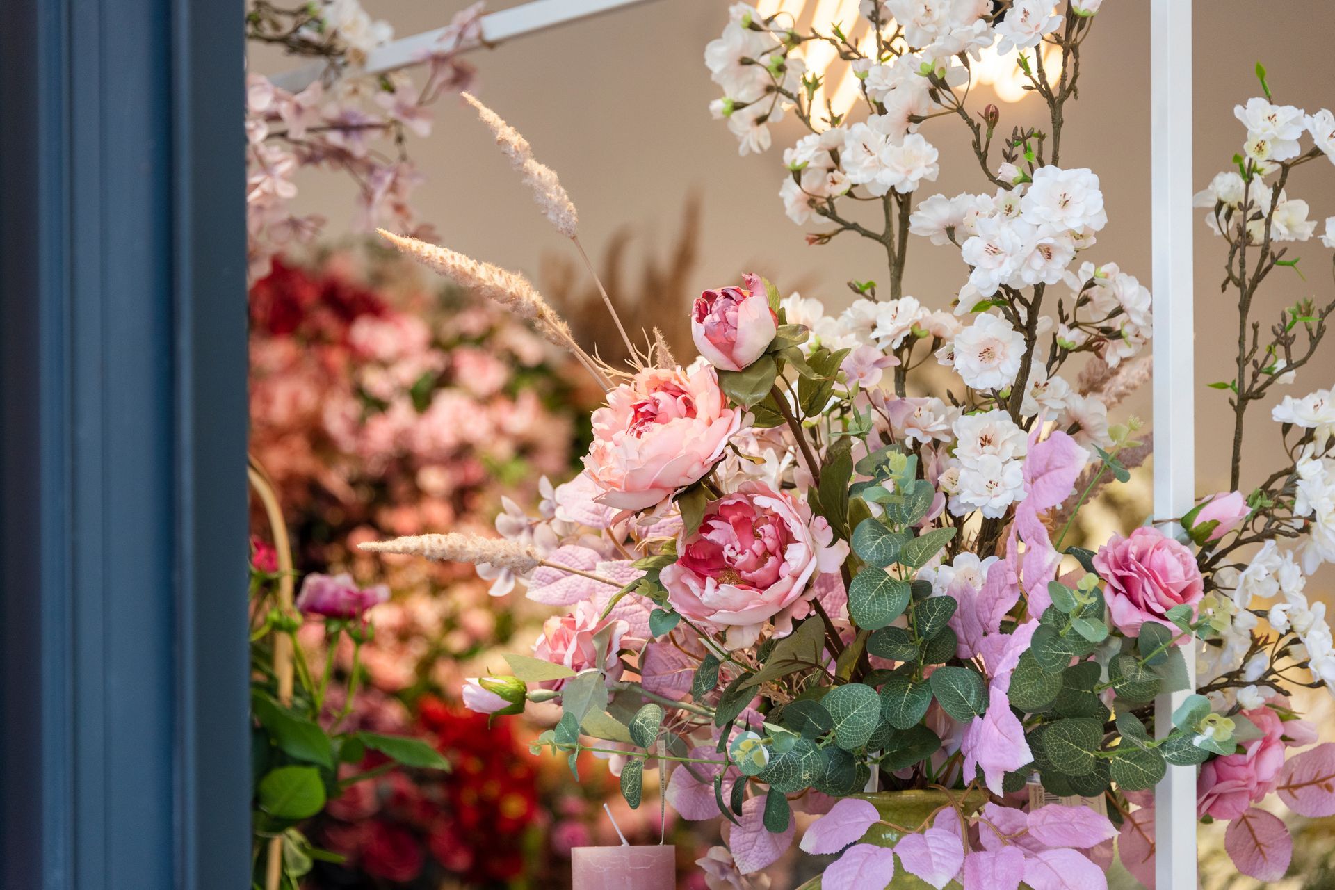 A vase filled with pink and white flowers is sitting in front of a window.