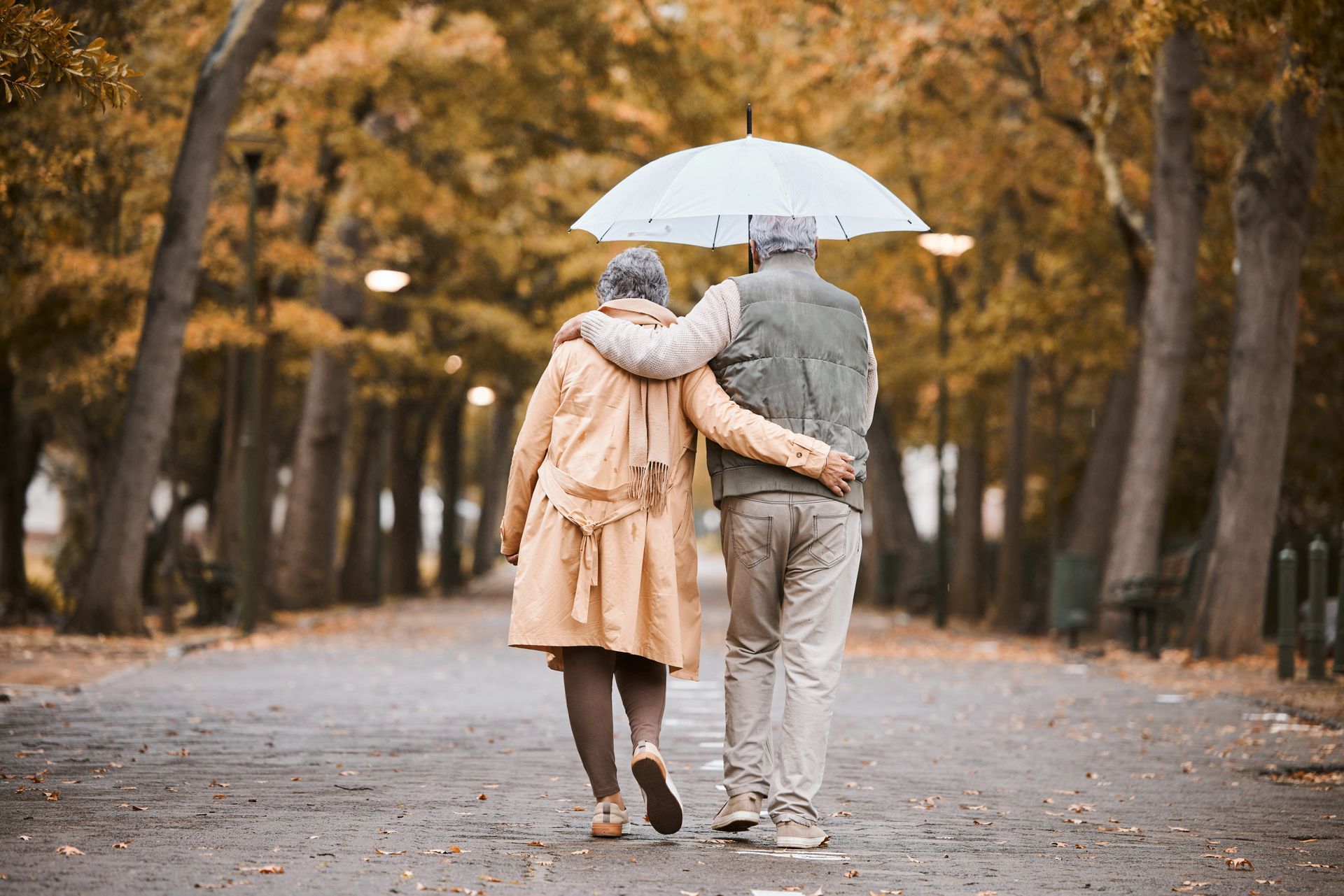 A man and a woman are walking in the rain with an umbrella.