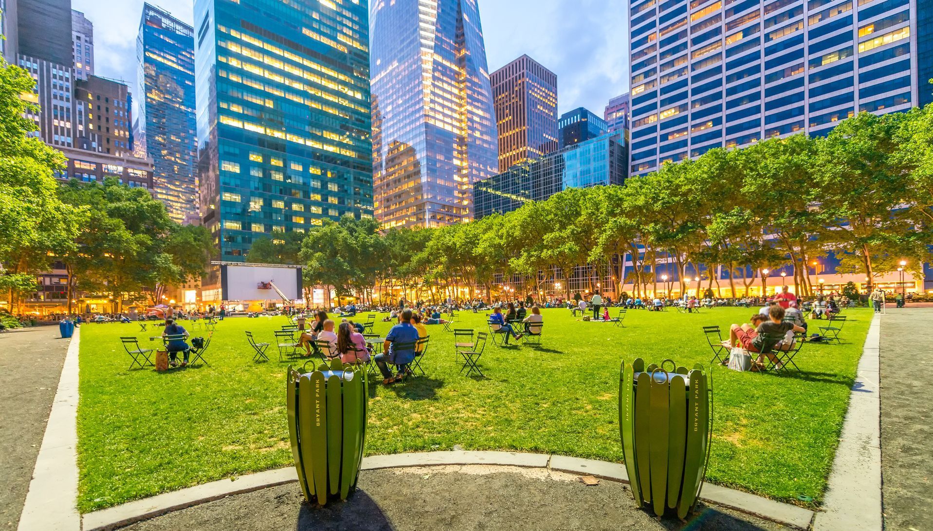 A group of people are sitting in a park with a city skyline in the background.