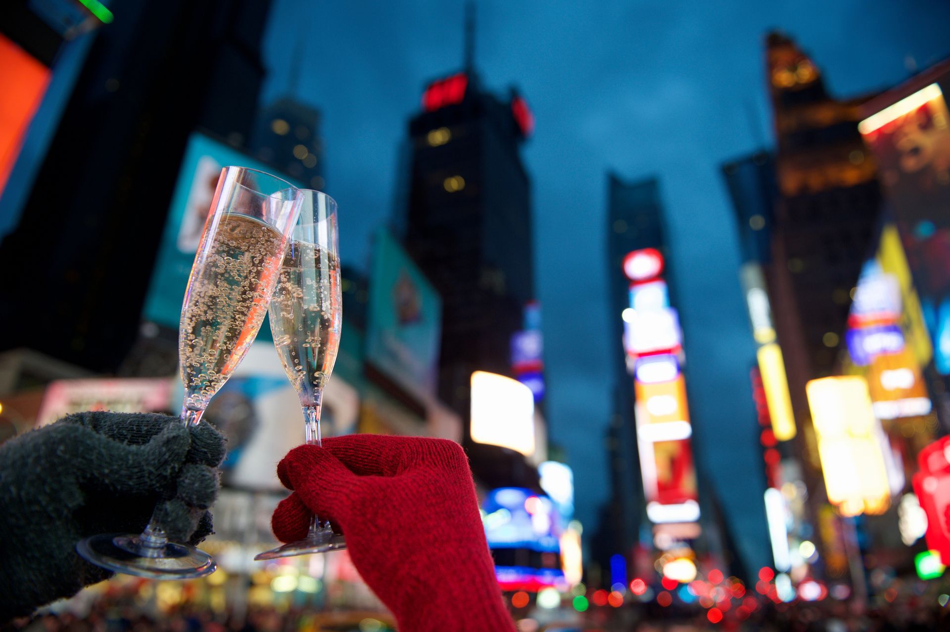 Two people are holding champagne glasses in front of a city skyline.