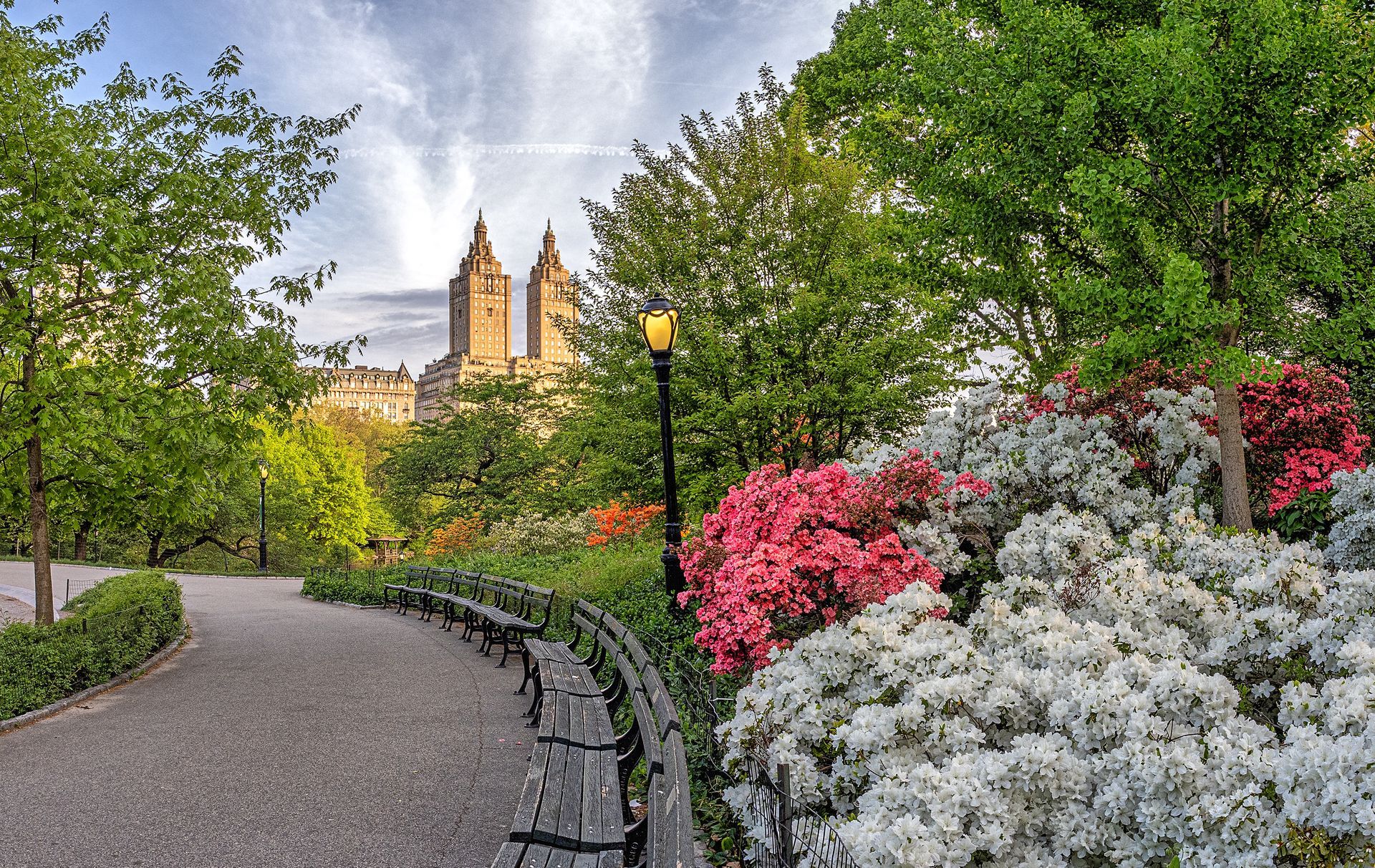 A park with a bench and flowers in the foreground and a castle in the background.